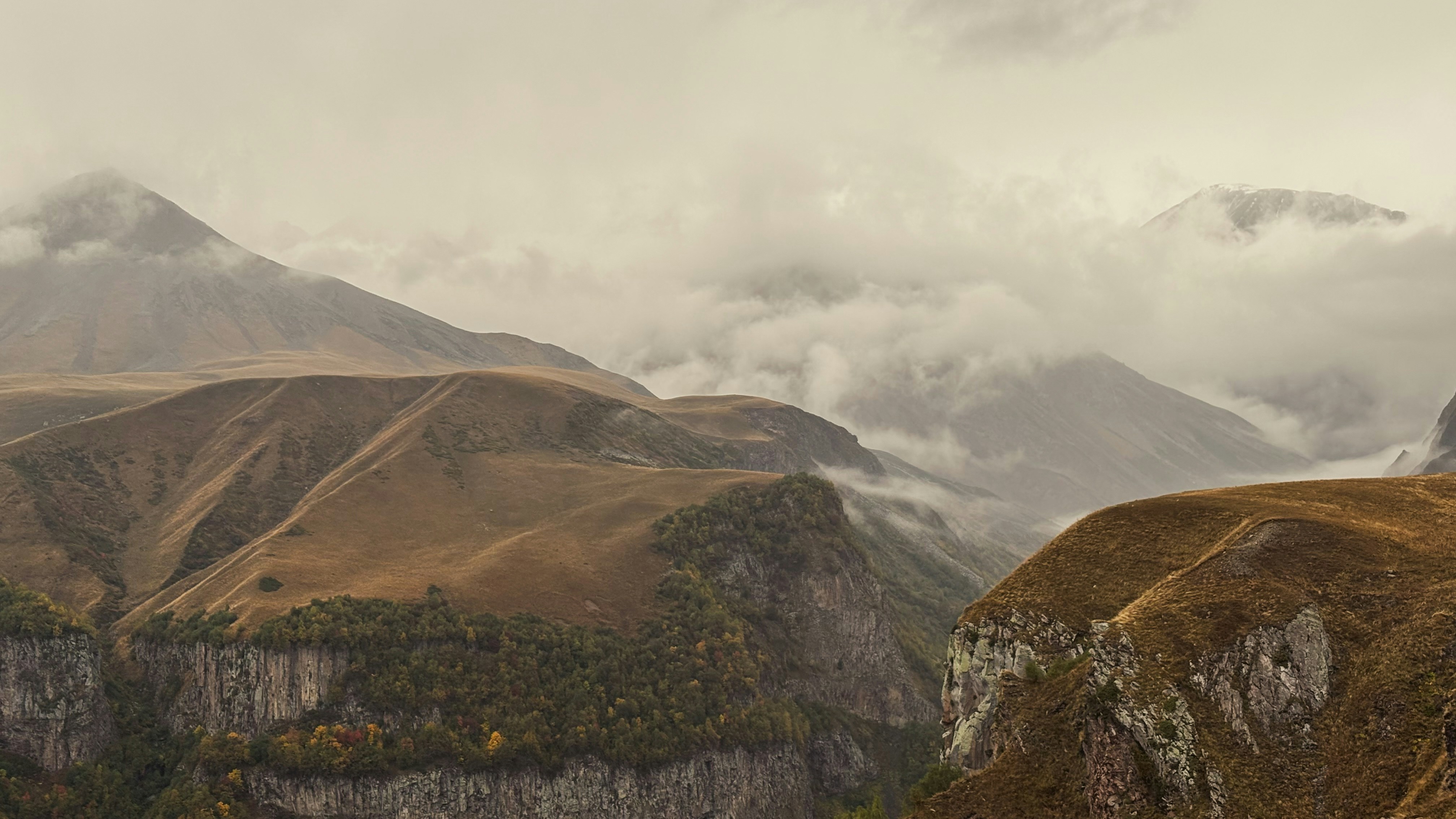 Misty mountains with rugged, brown slopes and cliffs