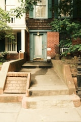 A brick house with a light blue door and stairs.