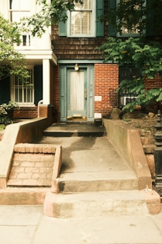A brick house with a light blue door and stairs.