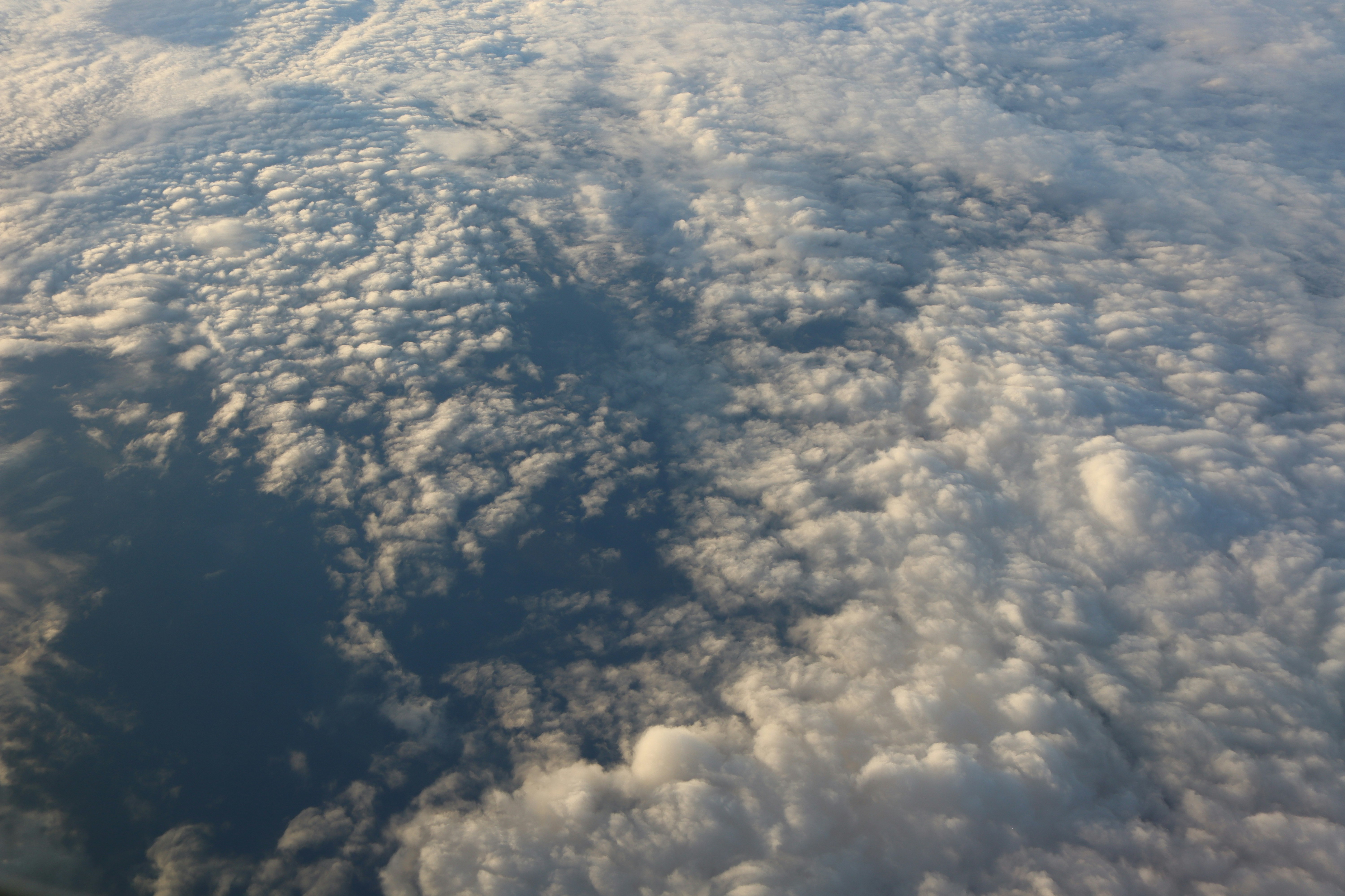 Fluffy white clouds drift over deep blue water.