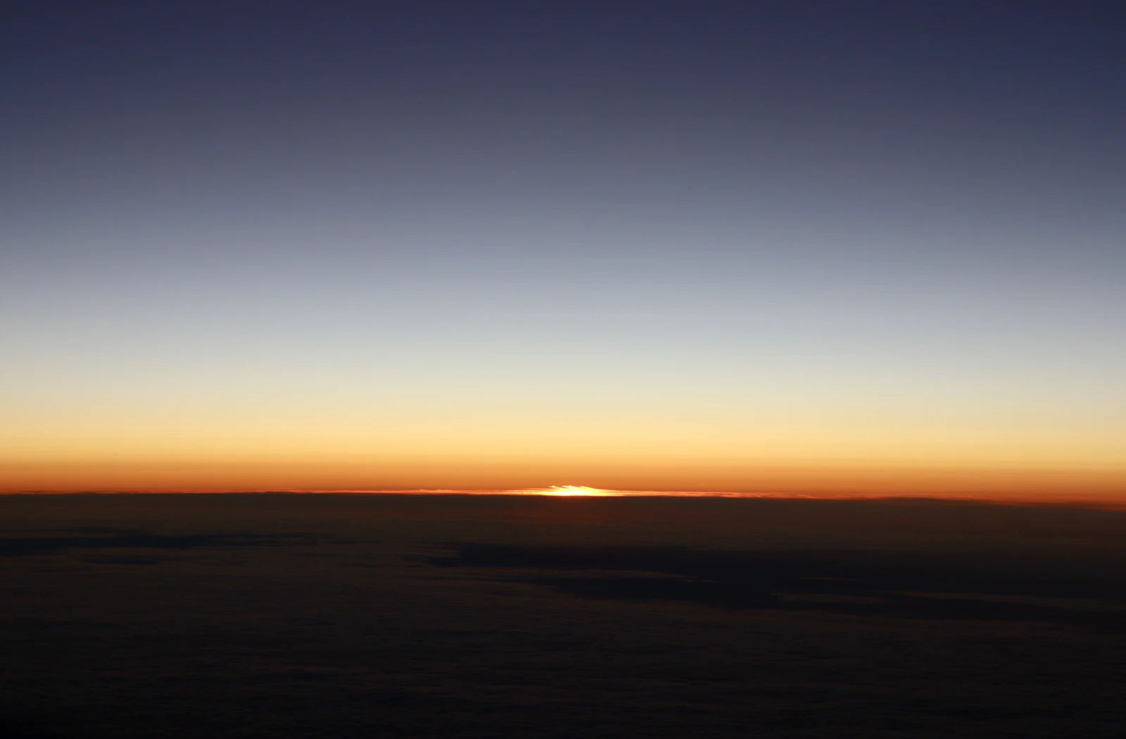Sunrise breaking over a layer of clouds on the horizon at dawn