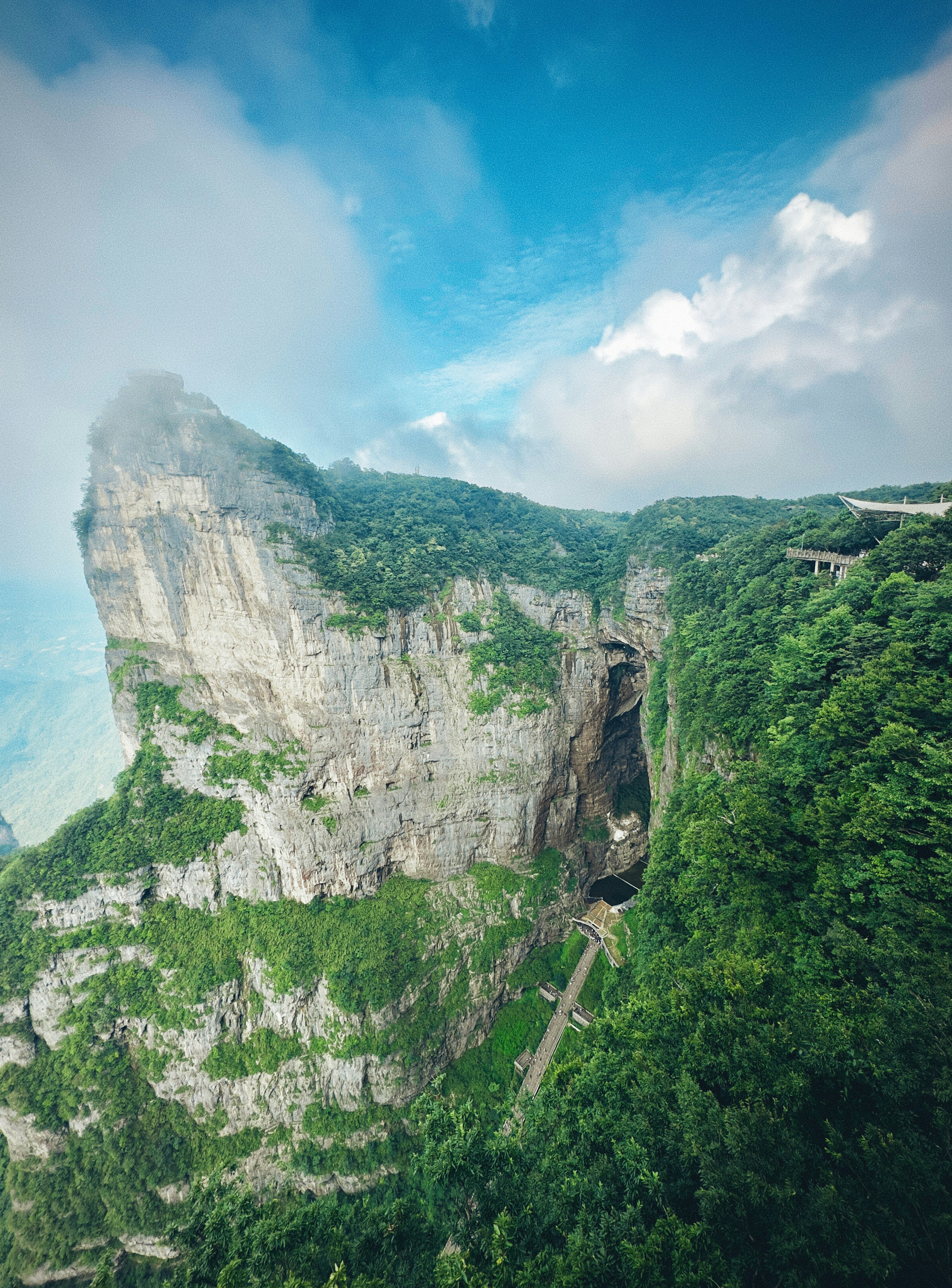 Towering green cliffs with a deep chasm under blue sky