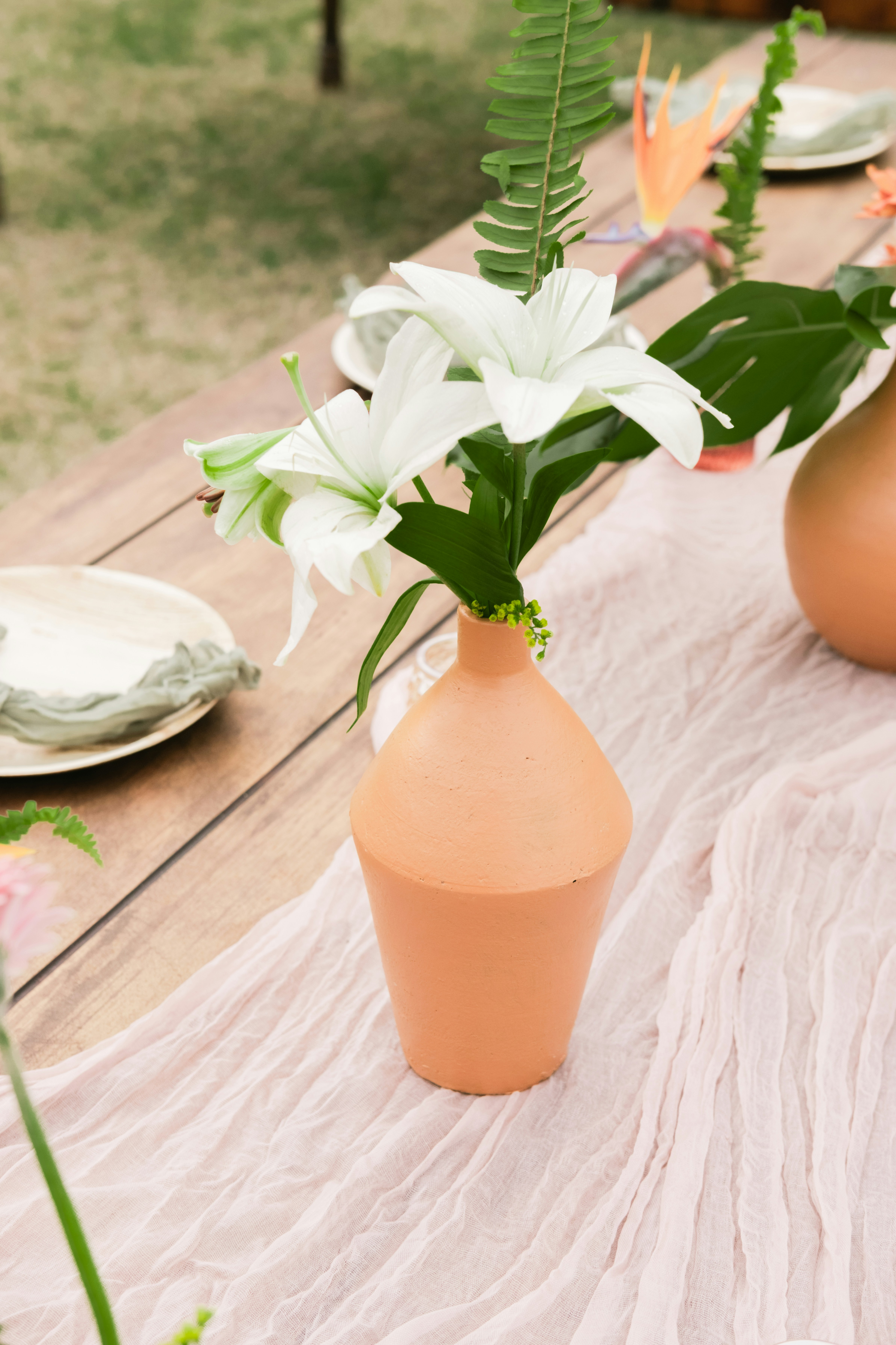 White lilies in a terracotta vase on a table