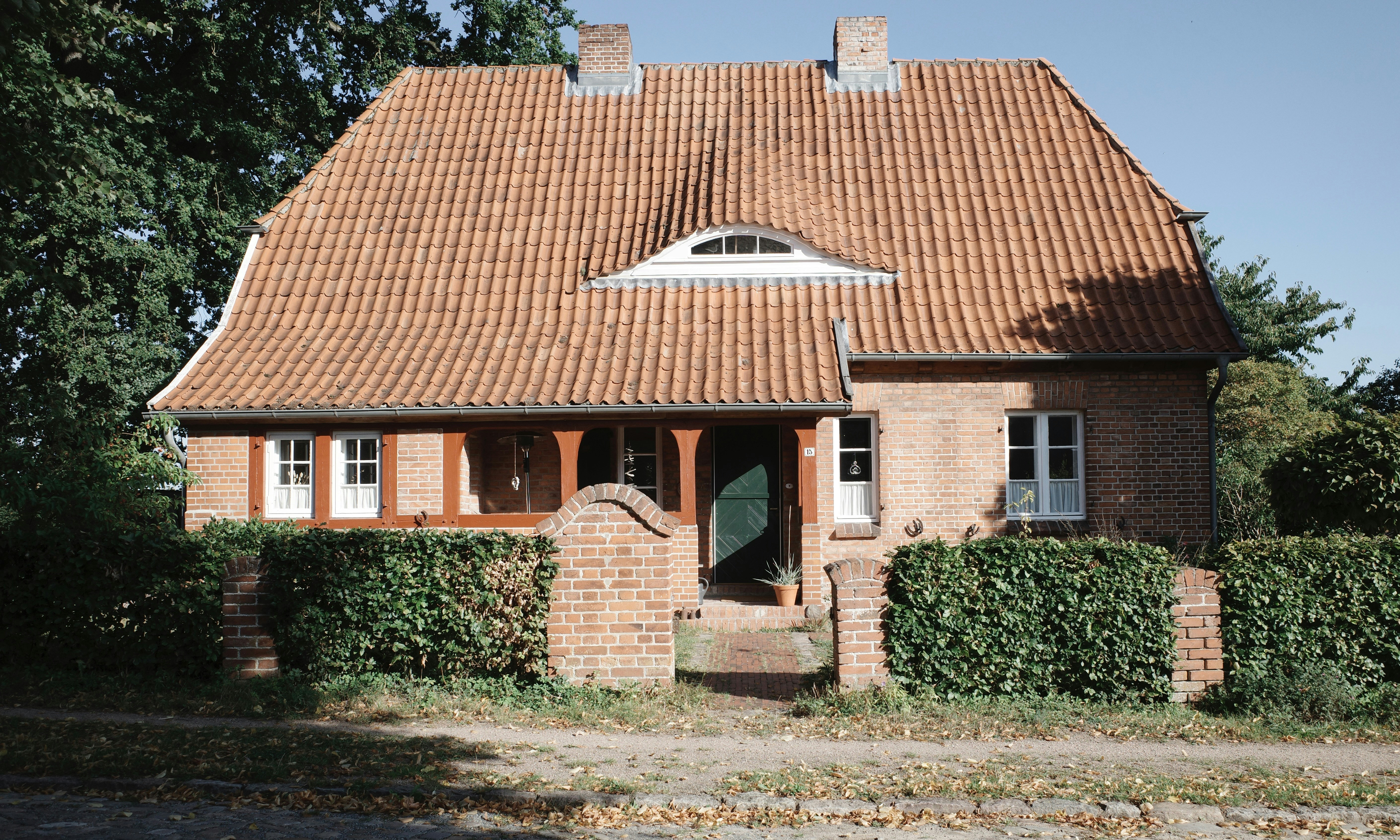 Casa de tijolos com telhado vermelho e porta verde.