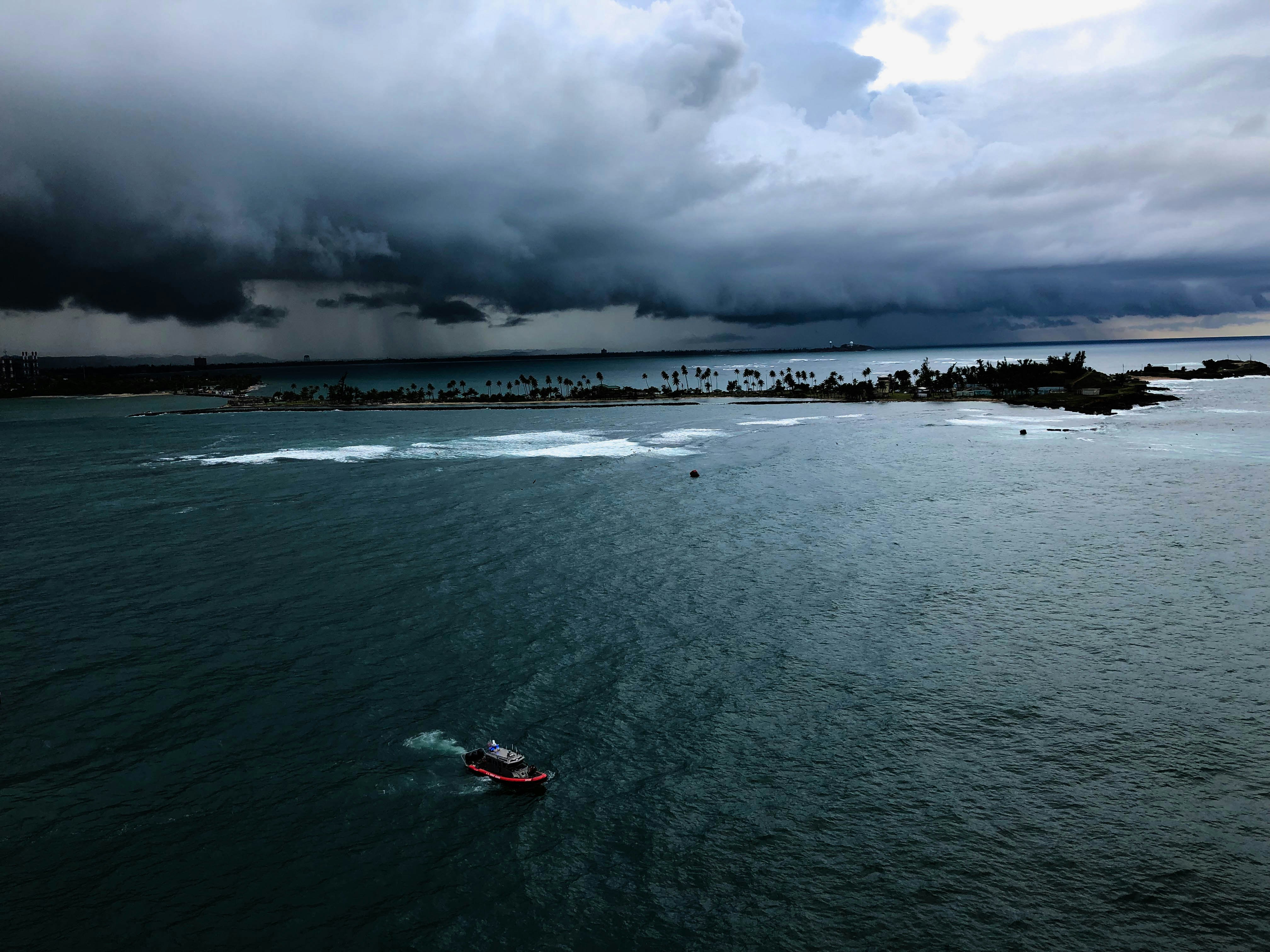 A small boat sails on the sea under stormy clouds.