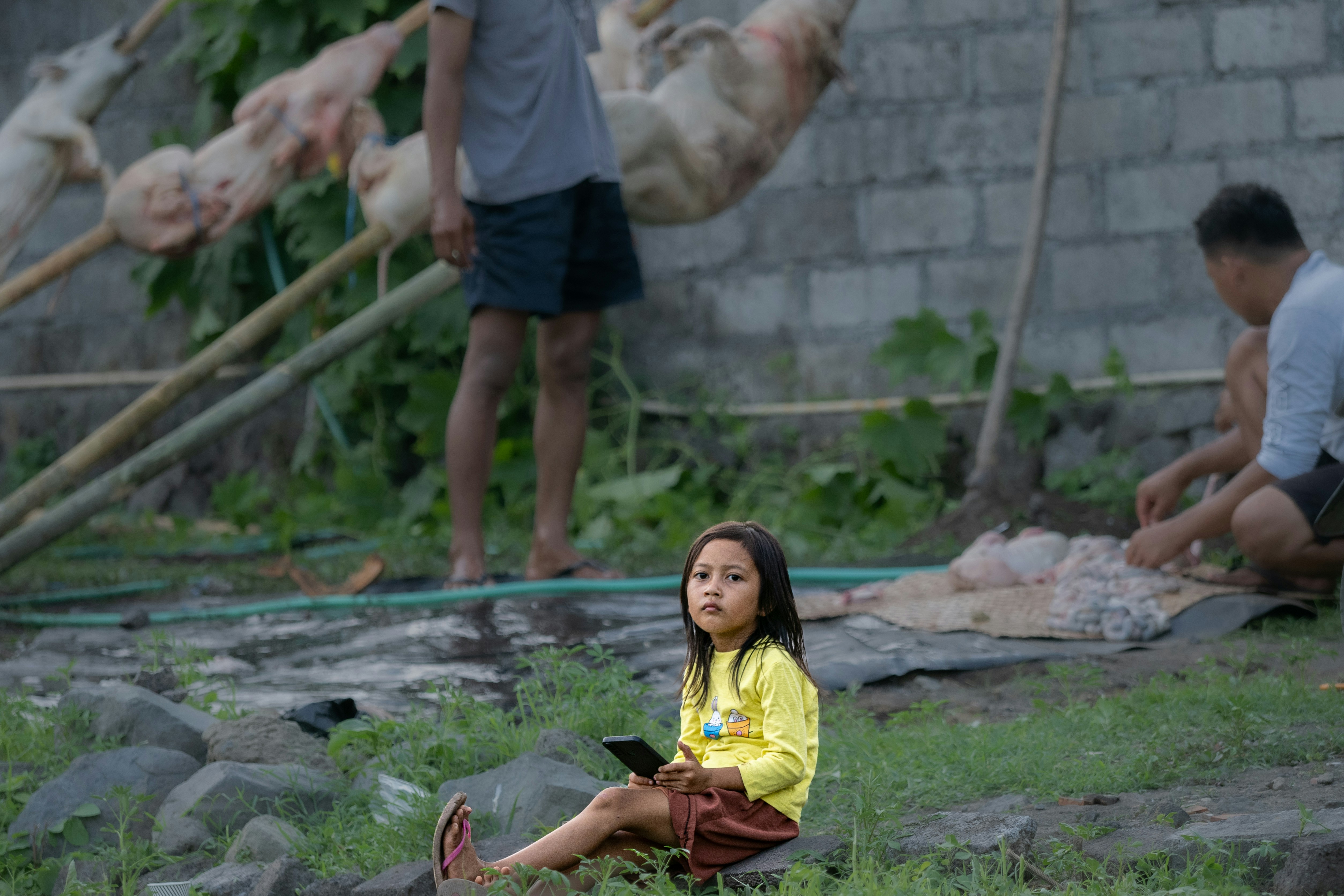 Young girl sits holding a smartphone outdoors.