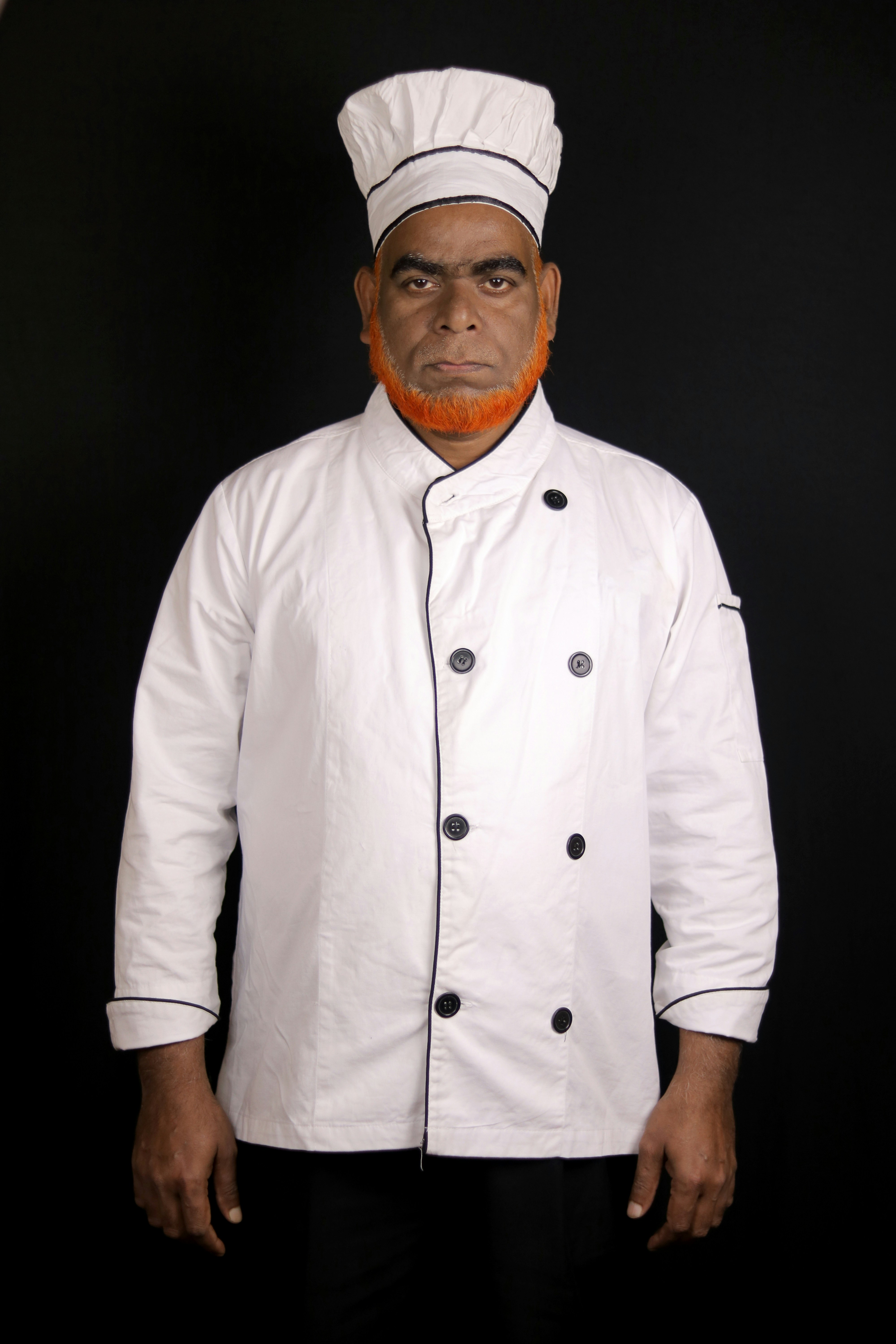 Ein Mann in Kochuniform mit orangefarbenem Bart.
