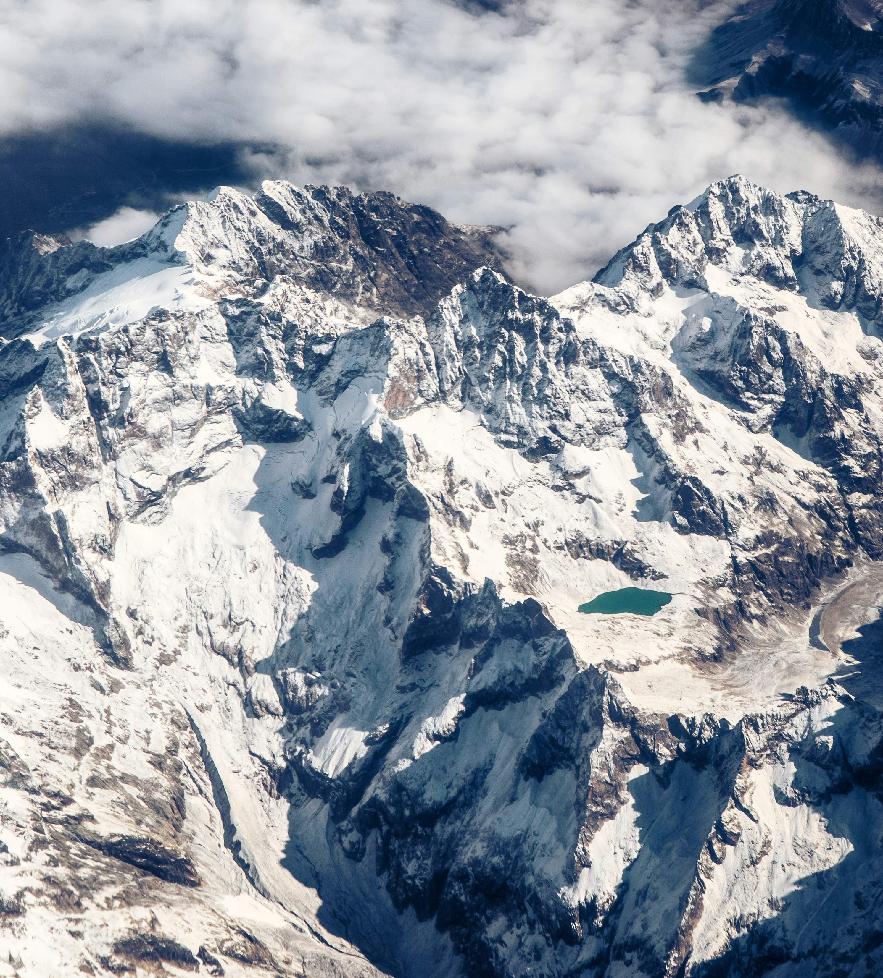 Snow-covered mountains with a small turquoise lake.