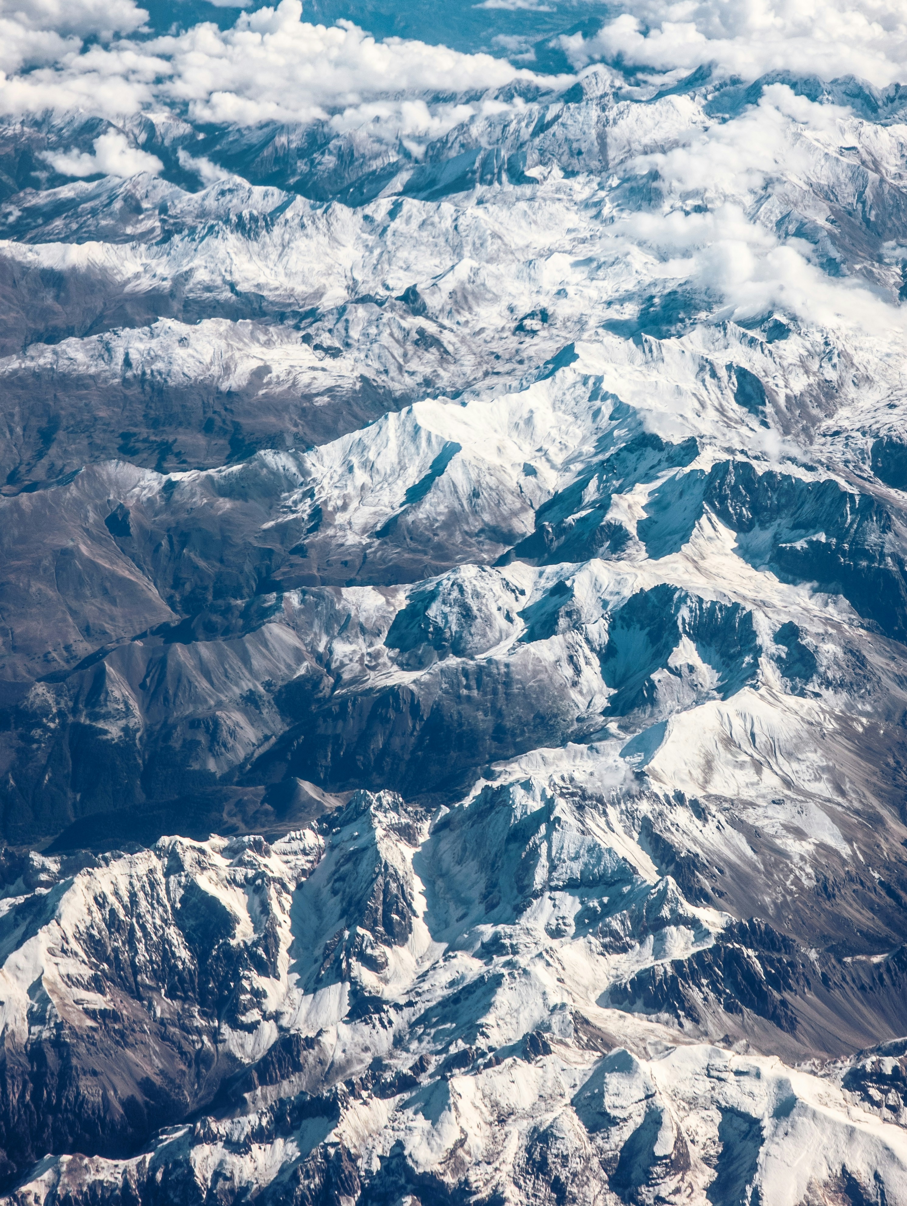 Aerial view of snow-capped mountains under clouds