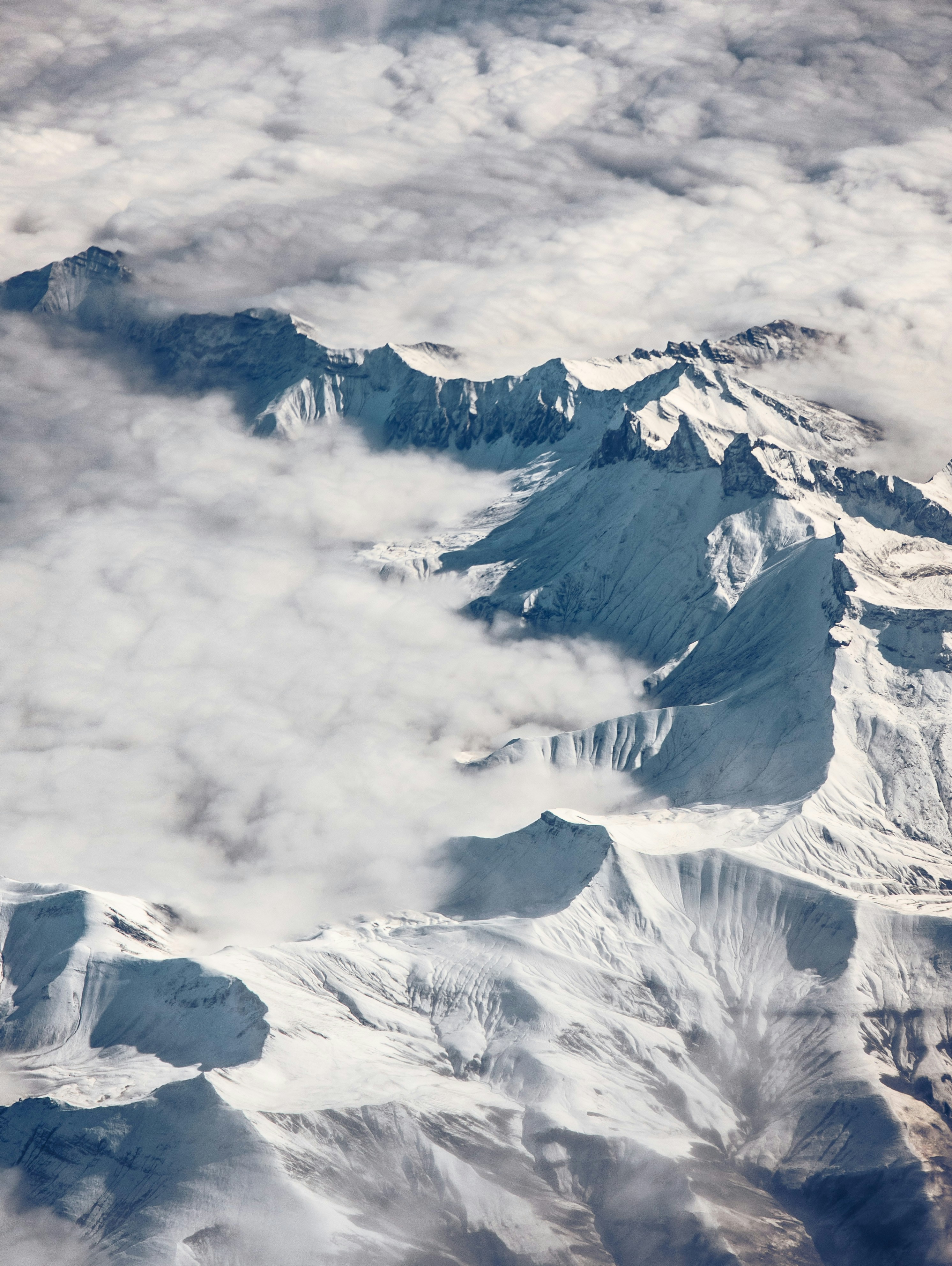 Snow-covered mountain range partially obscured by clouds.
