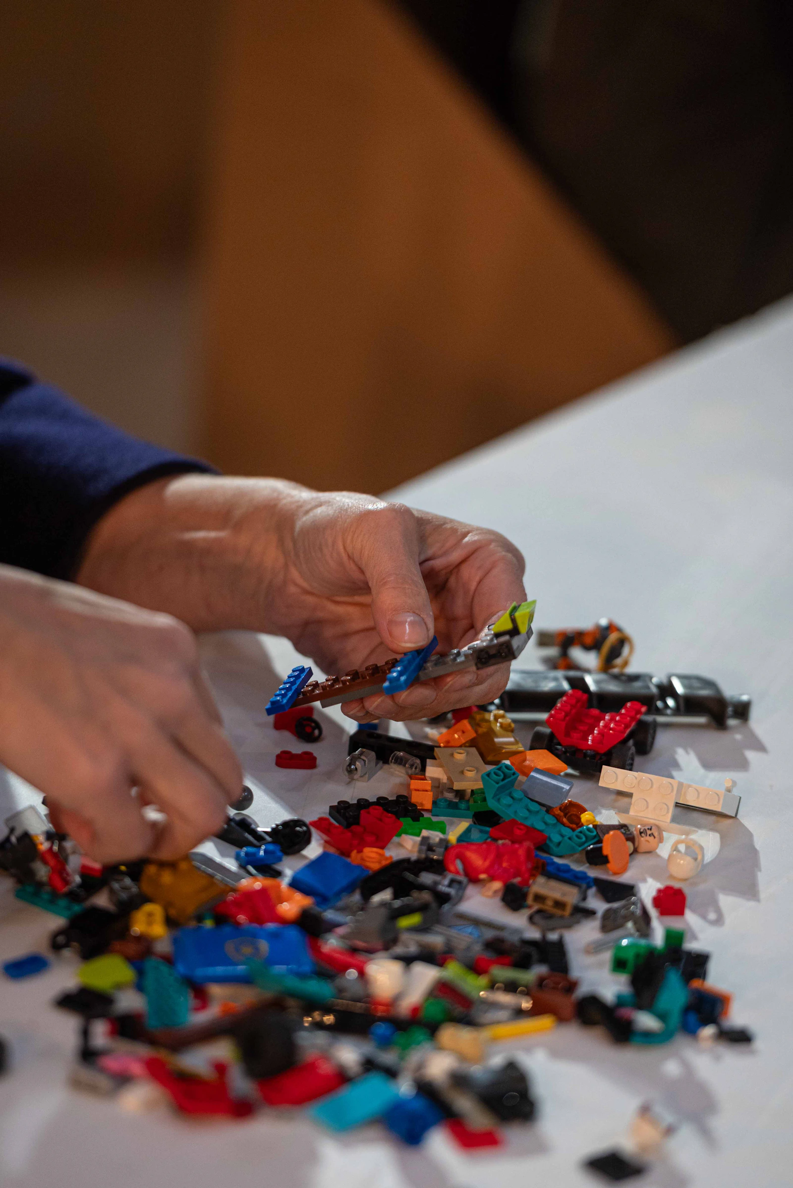 Hands assembling colorful construction pieces on a work surface