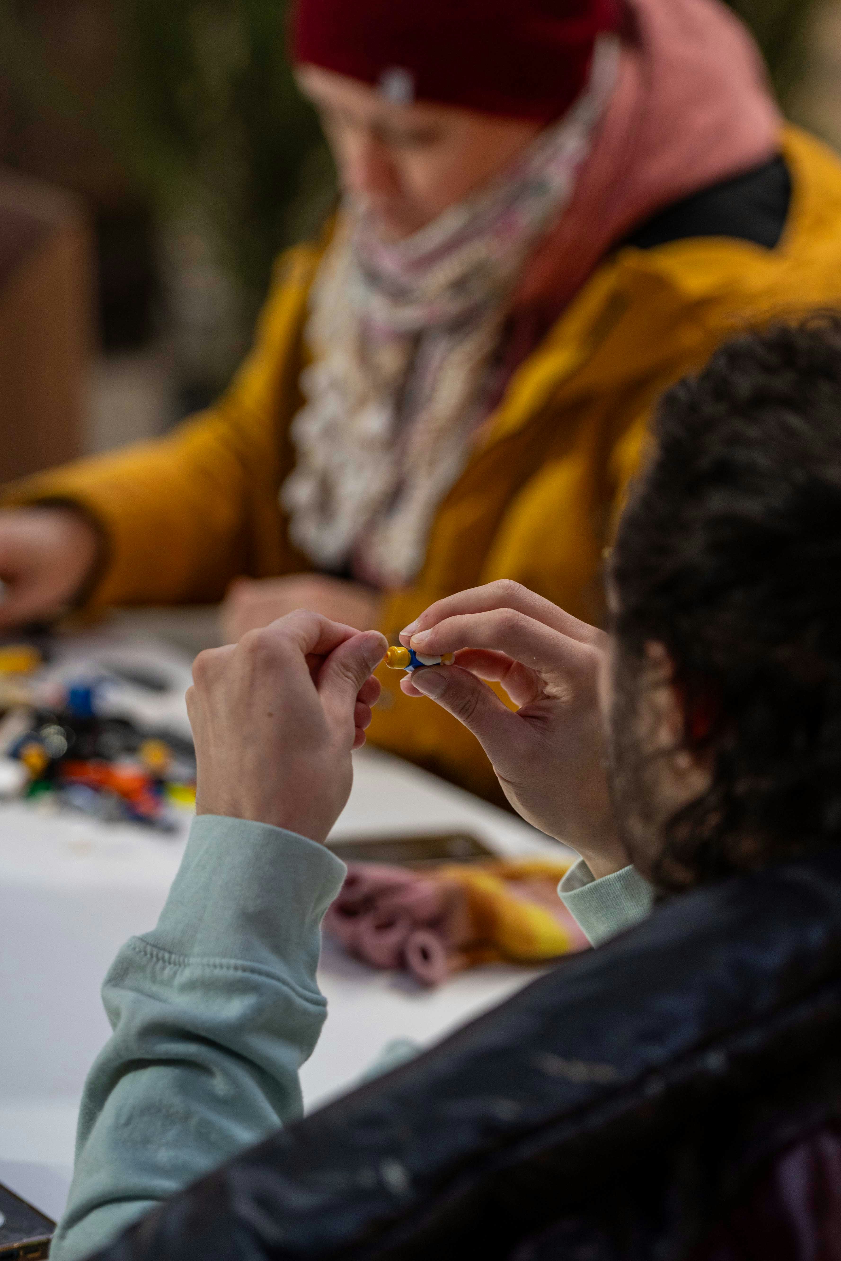 Mãos dos povos que montam partes coloridas pequenas na tabela