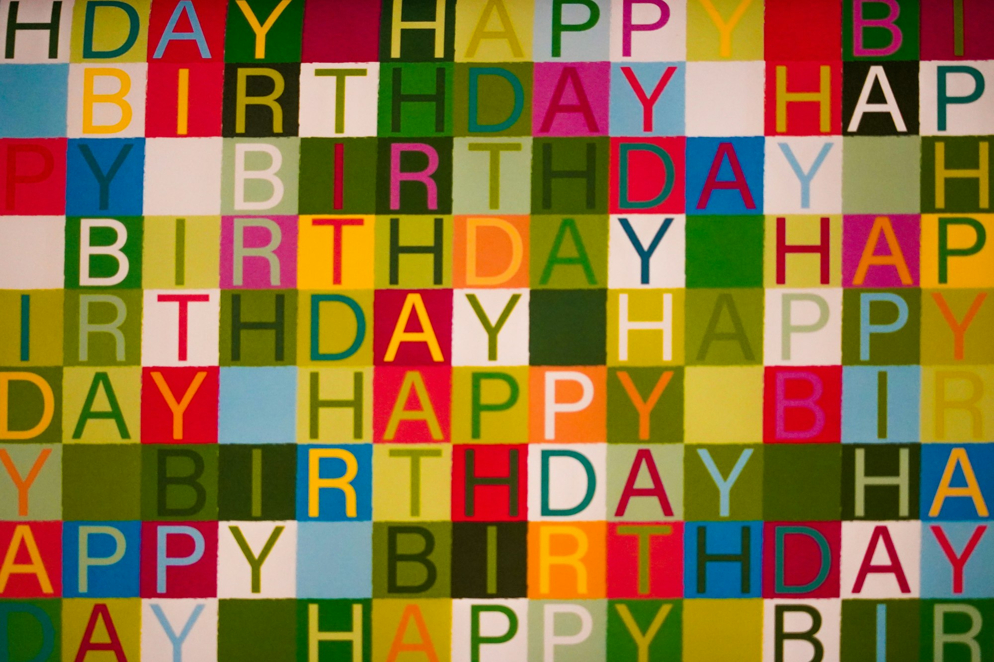 Colorful birthday text pattern with festive checkered background
