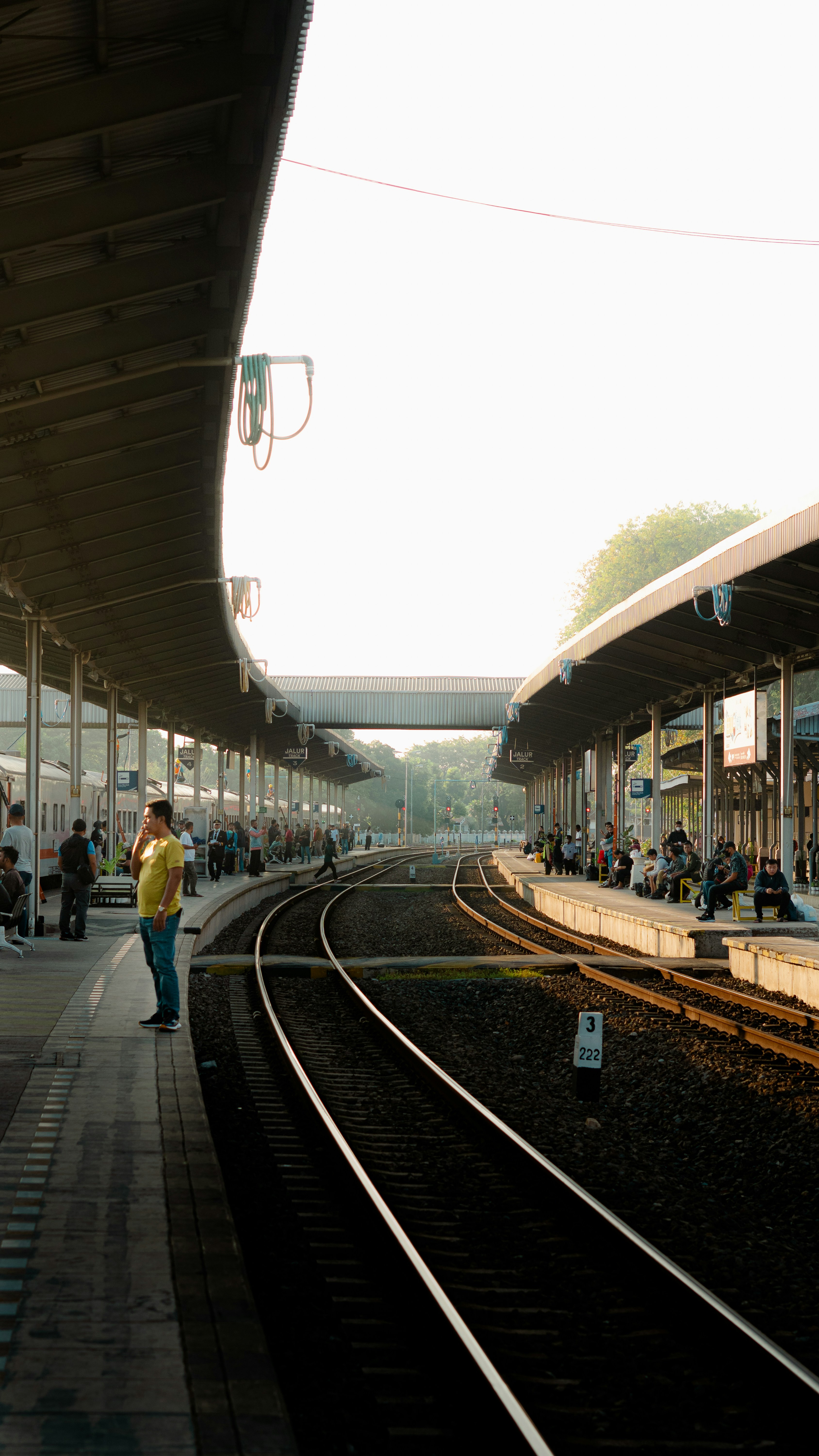 Bahnhof mit Gleisen und wartenden Passagieren im Unterstand