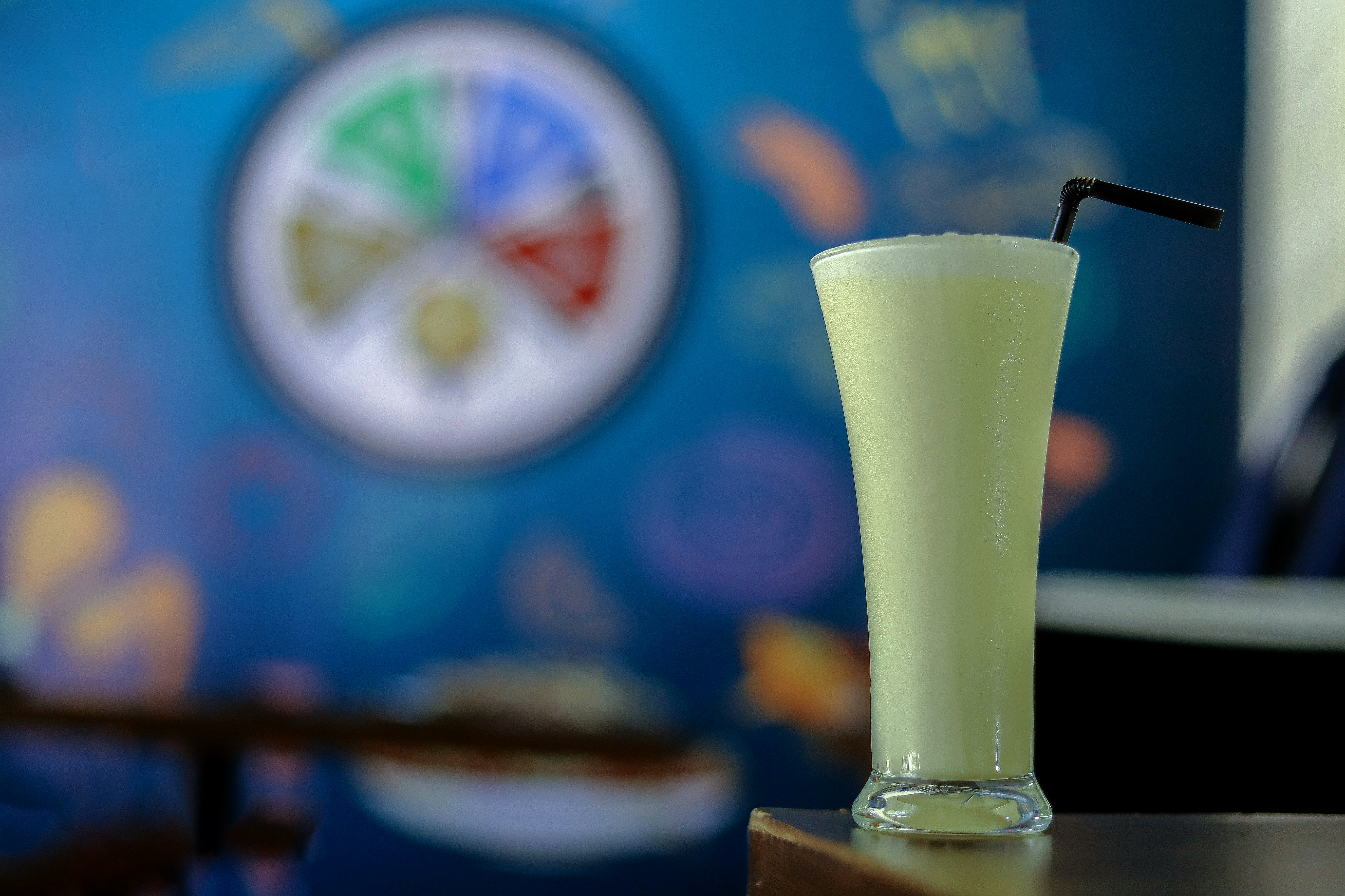 Un grand verre de smoothie vert pâle avec une paille.