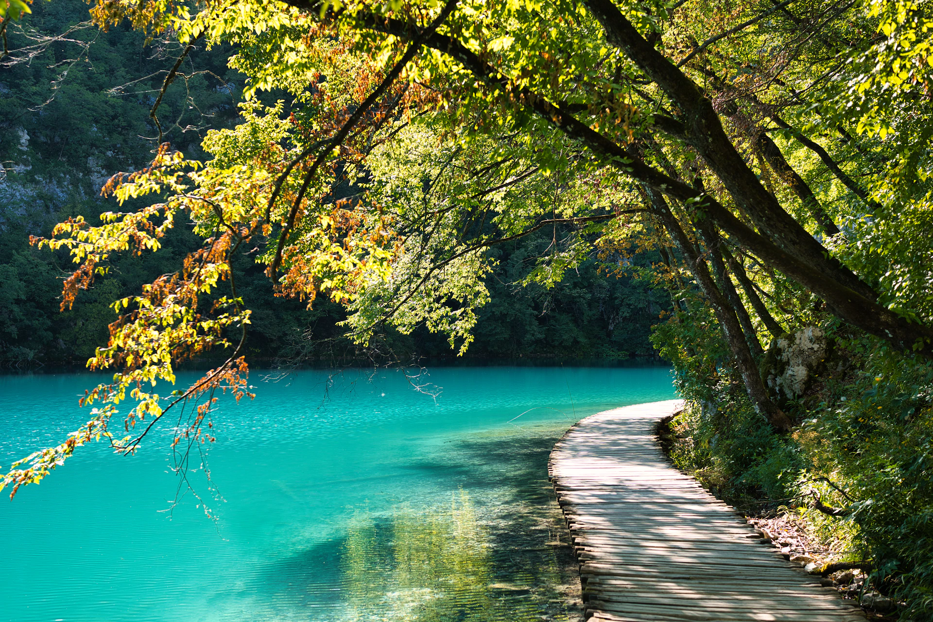 A paved path curves alongside a bright turquoise lake.