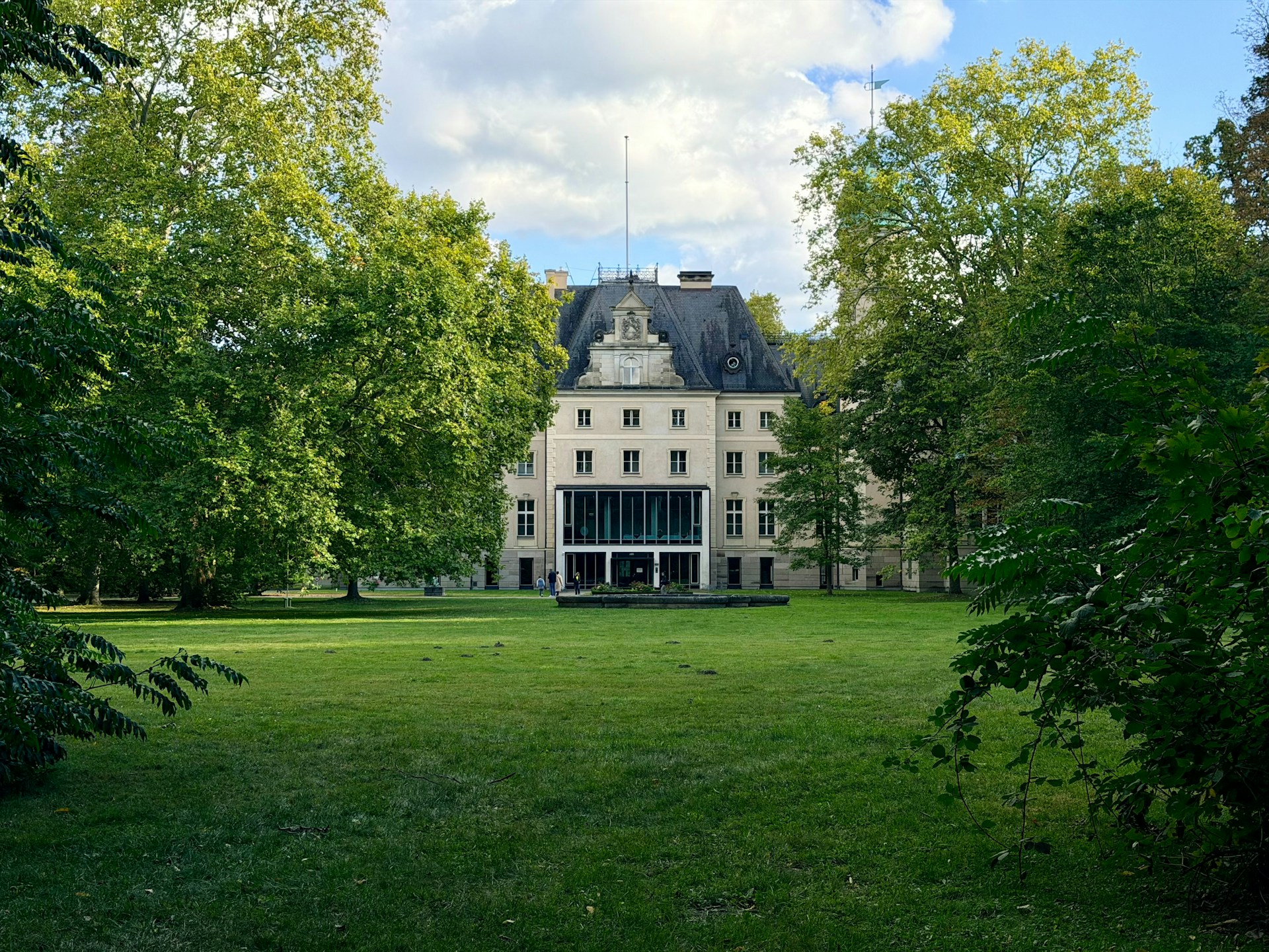 Grand building surrounded by lush green trees and lawn.