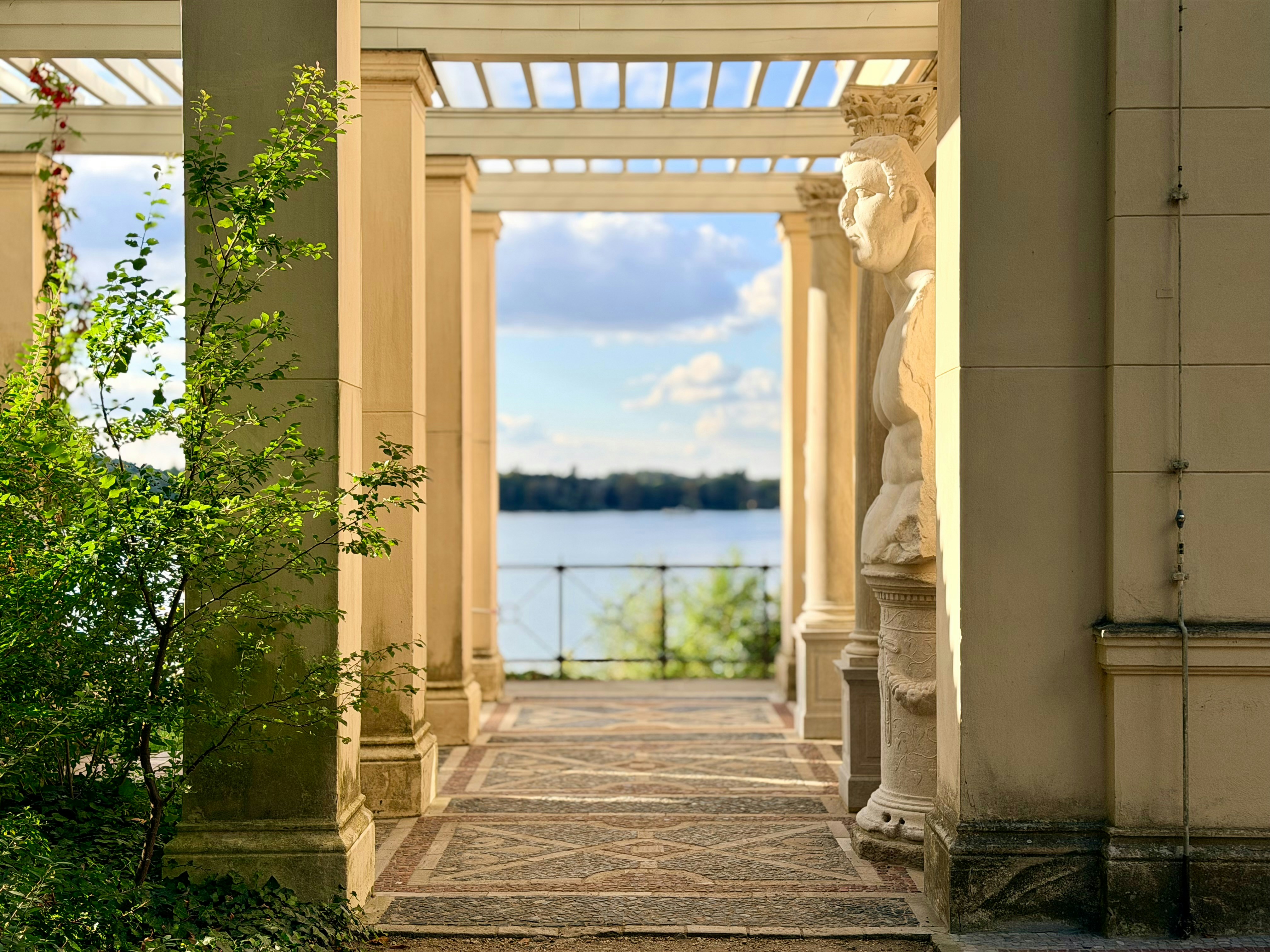 Colonnade overlooking a calm lake under a blue sky