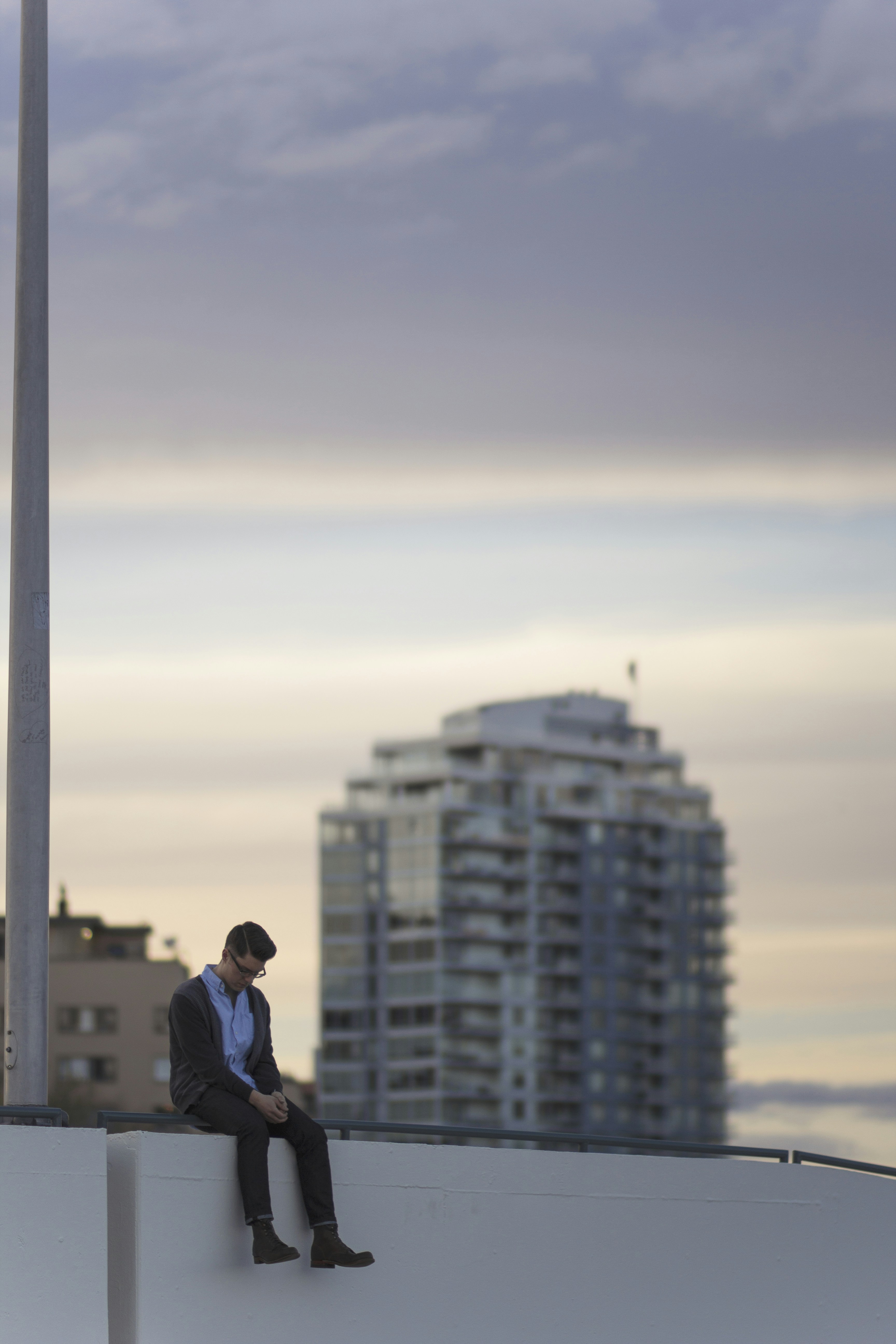 Homme assis sur le rebord avec des bâtiments de la ville derrière lui