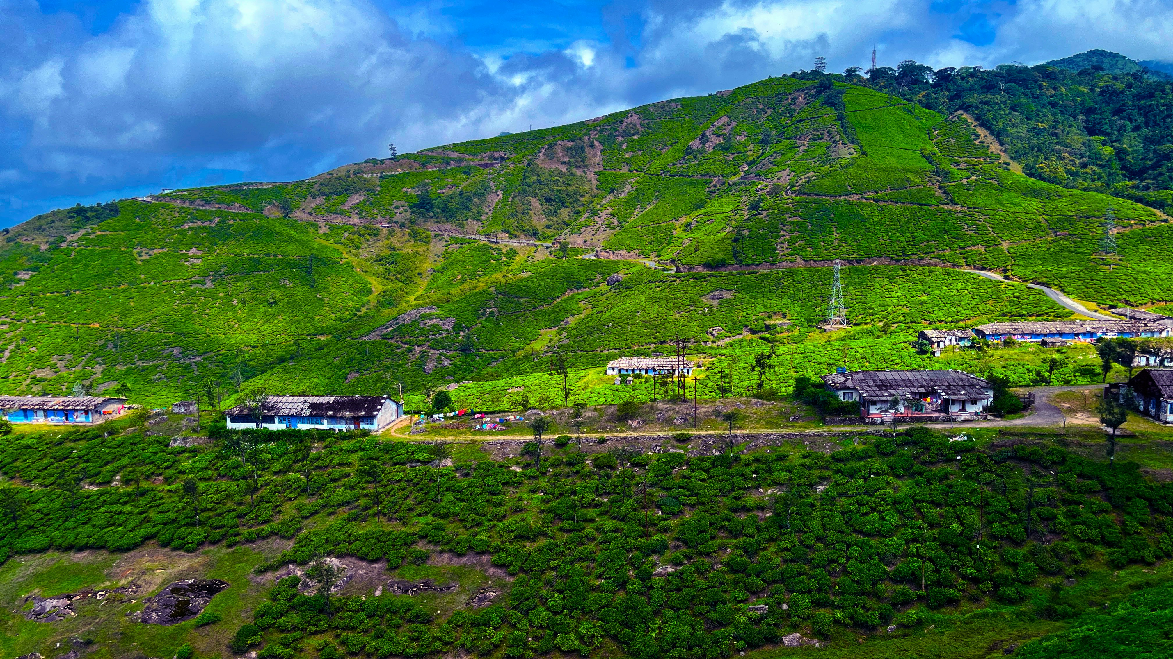 Green hills with scattered buildings under a cloudy sky
