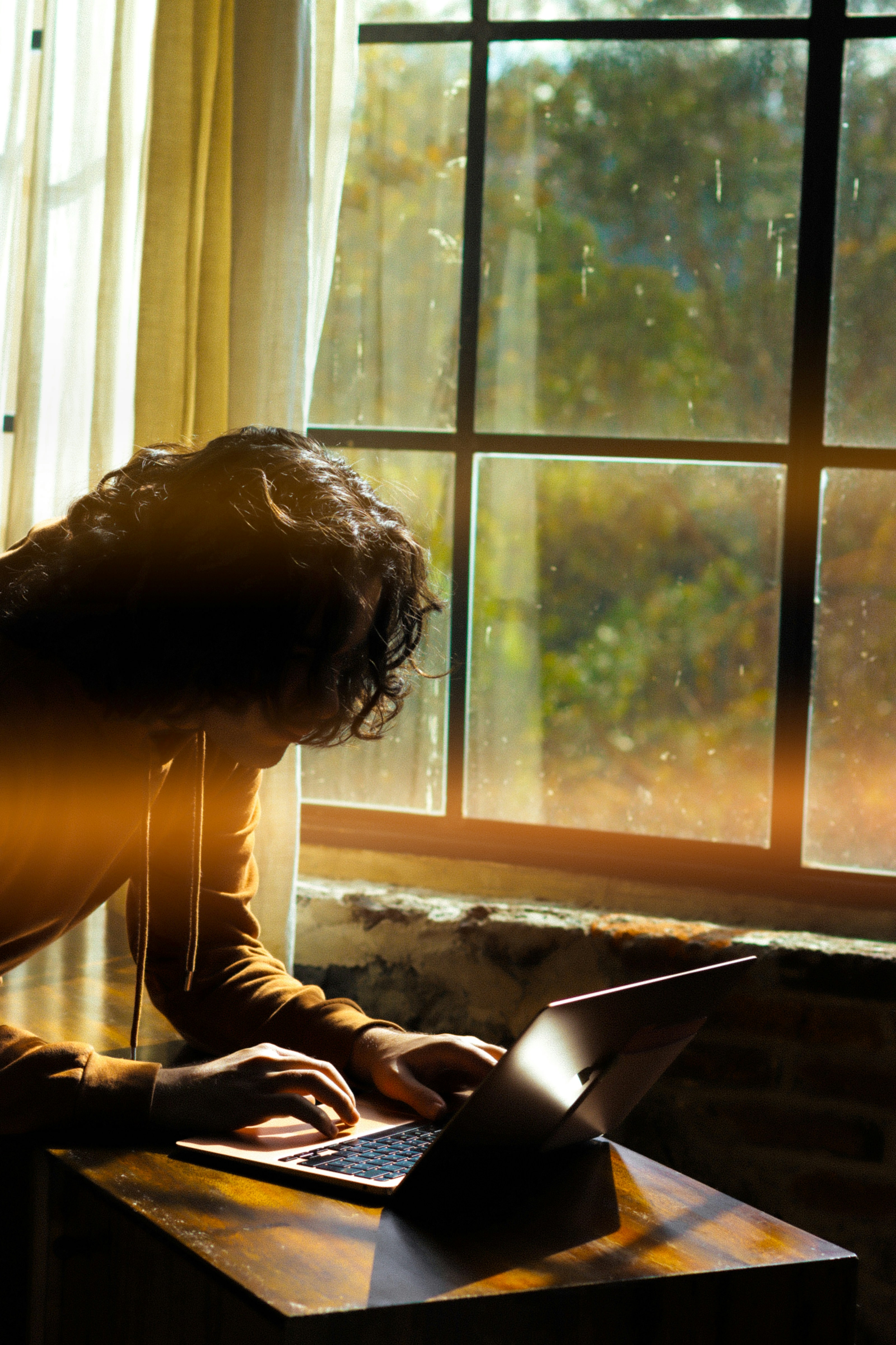 Person working on laptop by a sunlit window