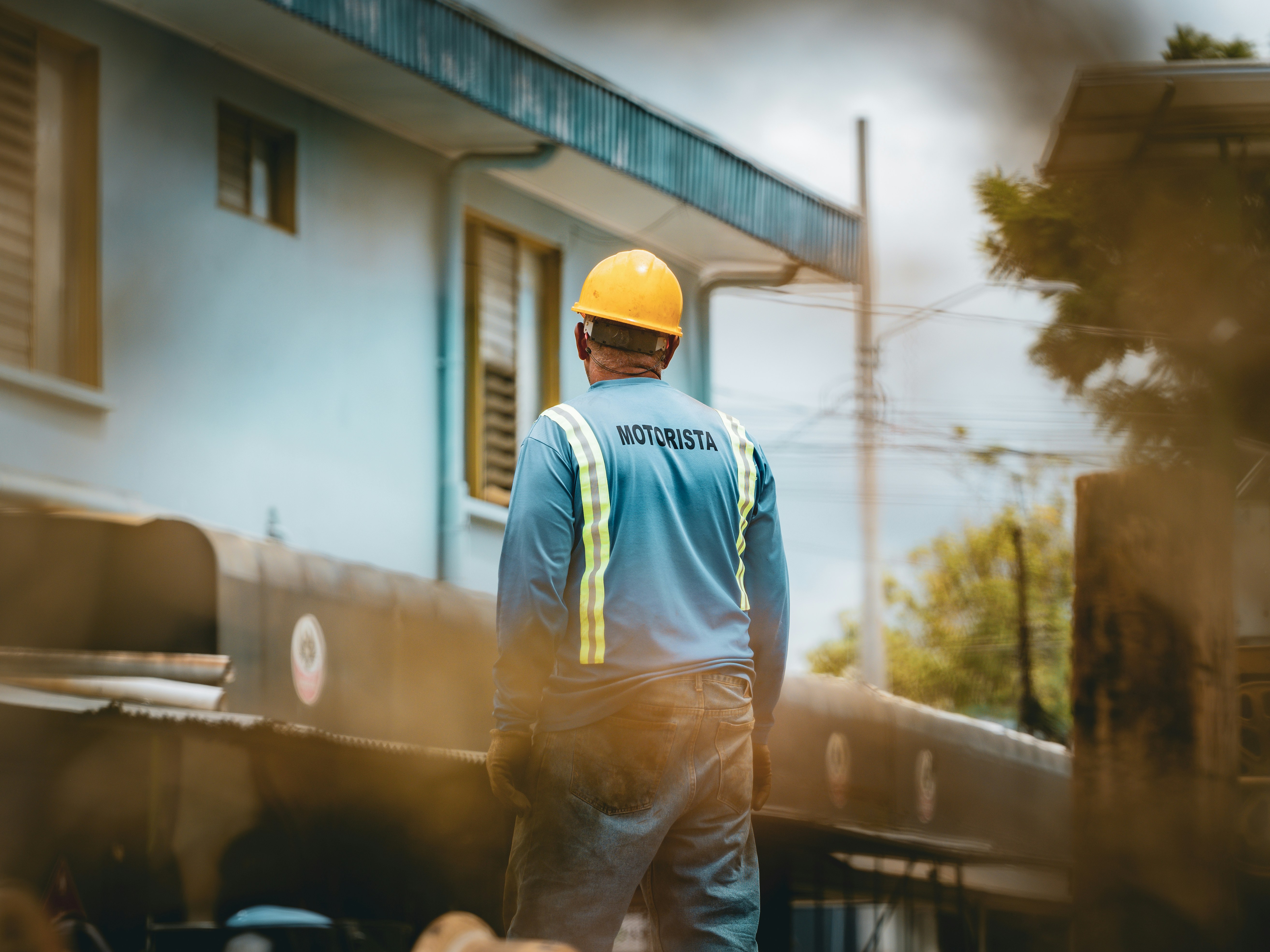 Worker in hard hat and safety vest looks away.