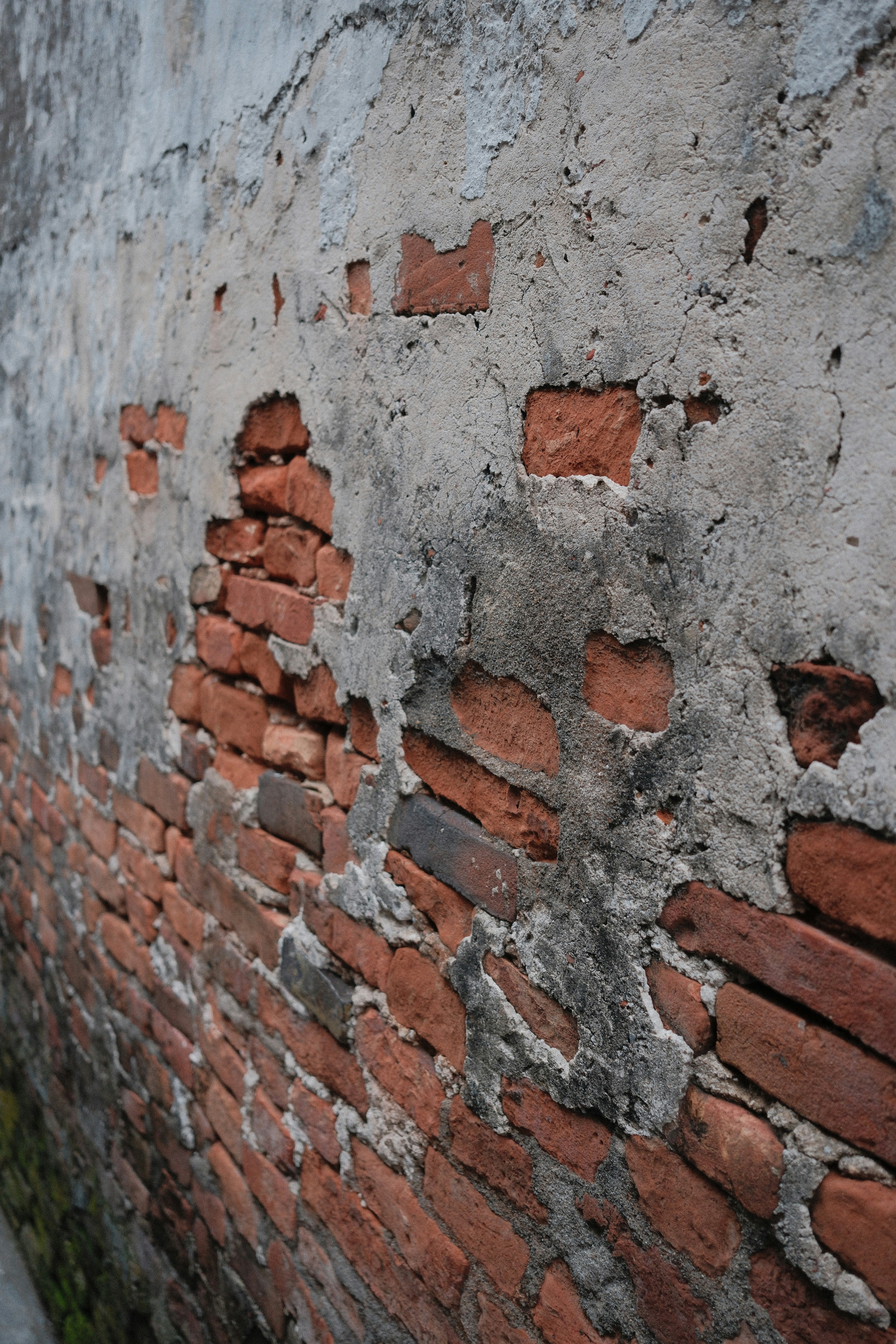 Weathered brick wall with crumbling concrete plaster