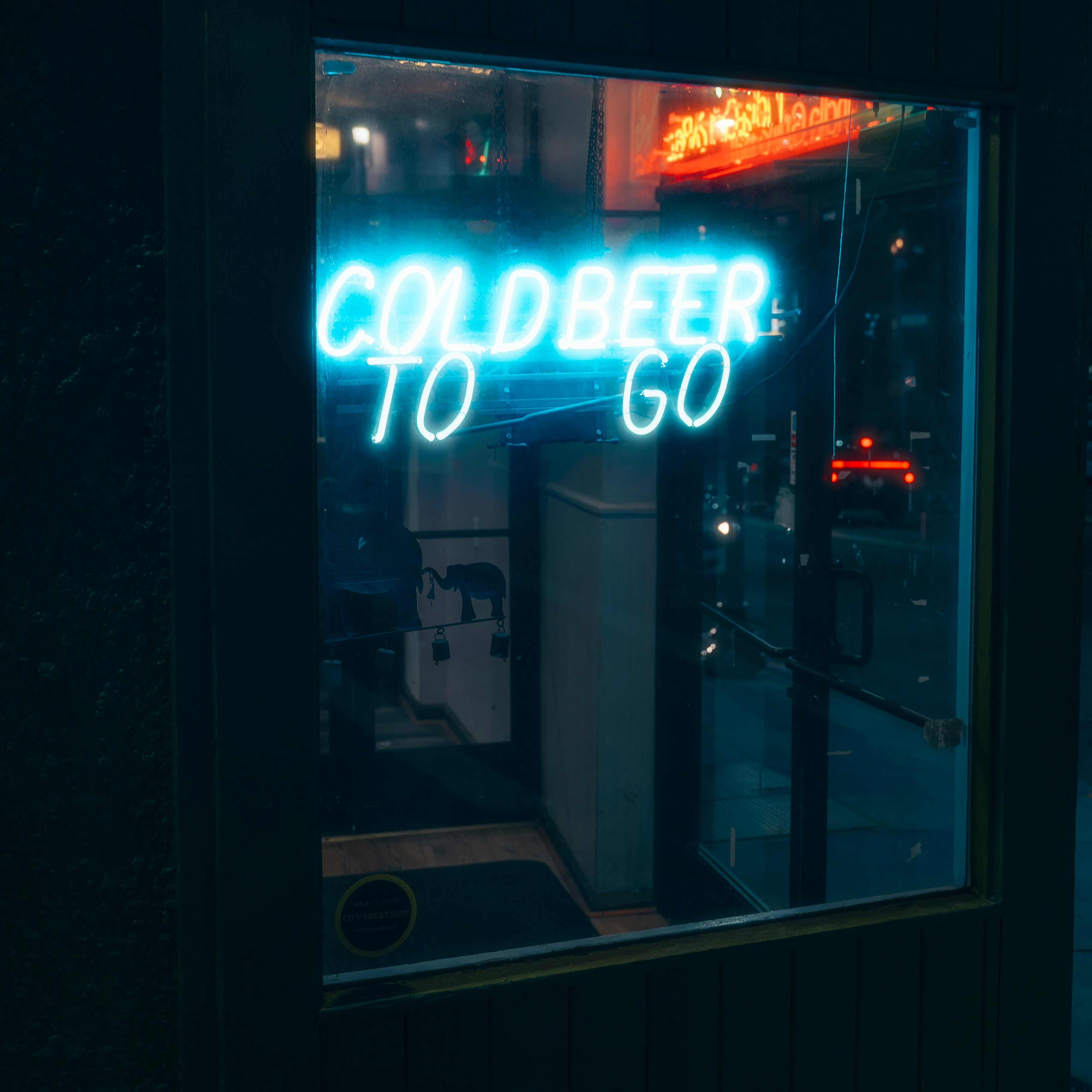 Neon sign reads "cold beer to go" at night."