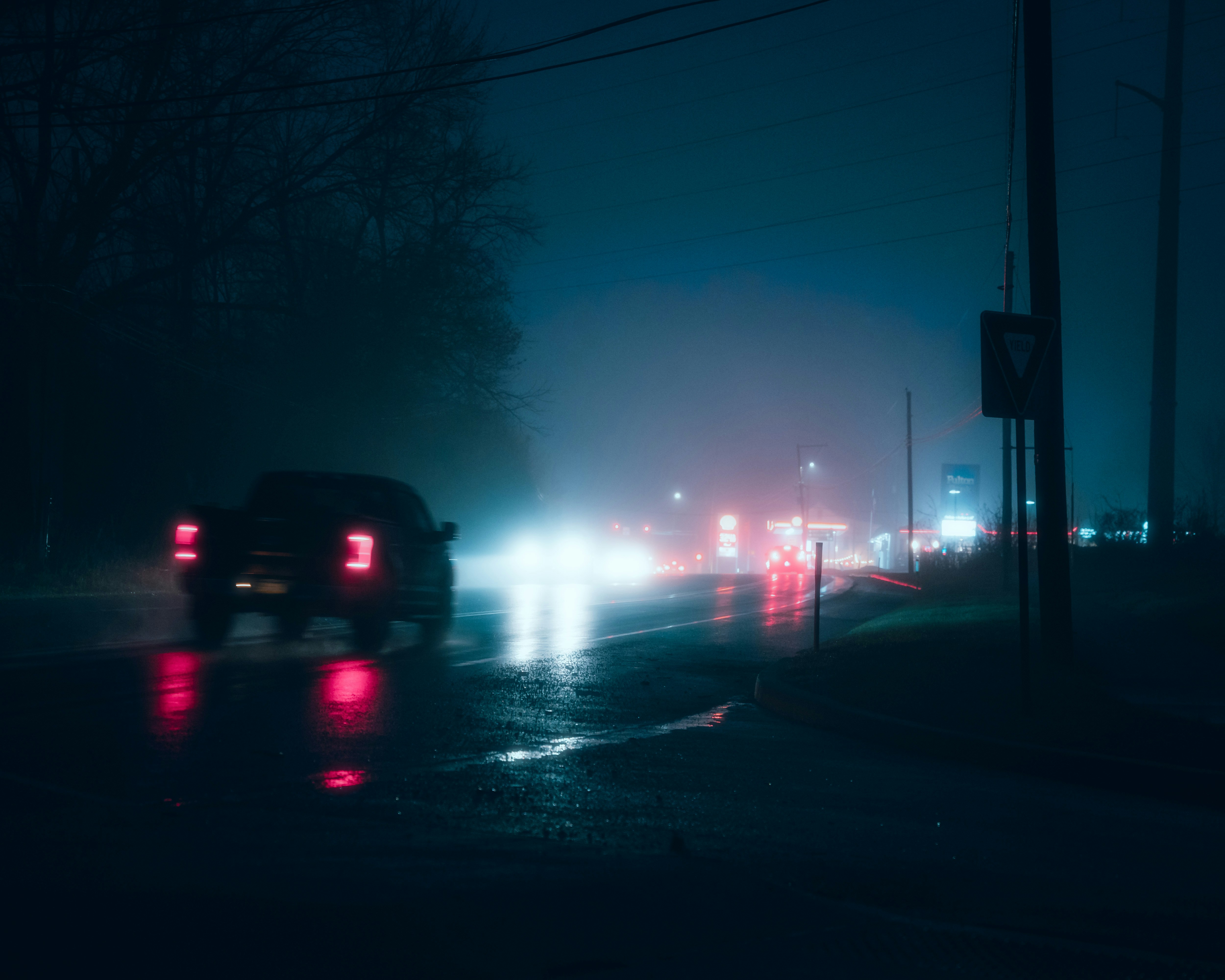 Cars driving on a wet road at night.