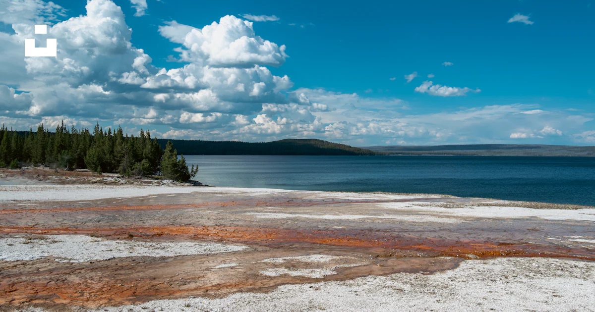 A scenic lake with colorful mineral deposits and pine trees. photo ...