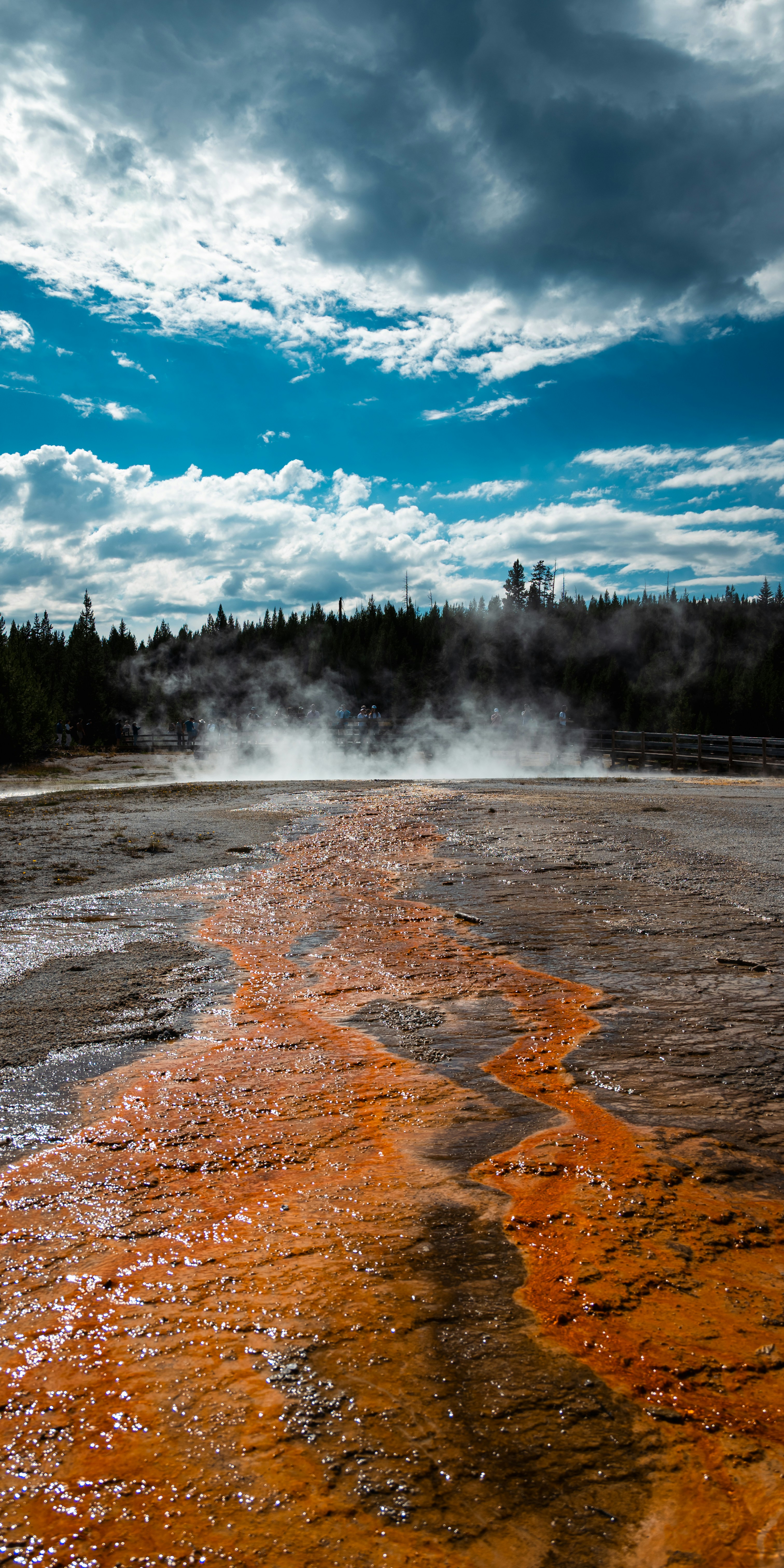 Steaming hot spring with orange mineral deposits