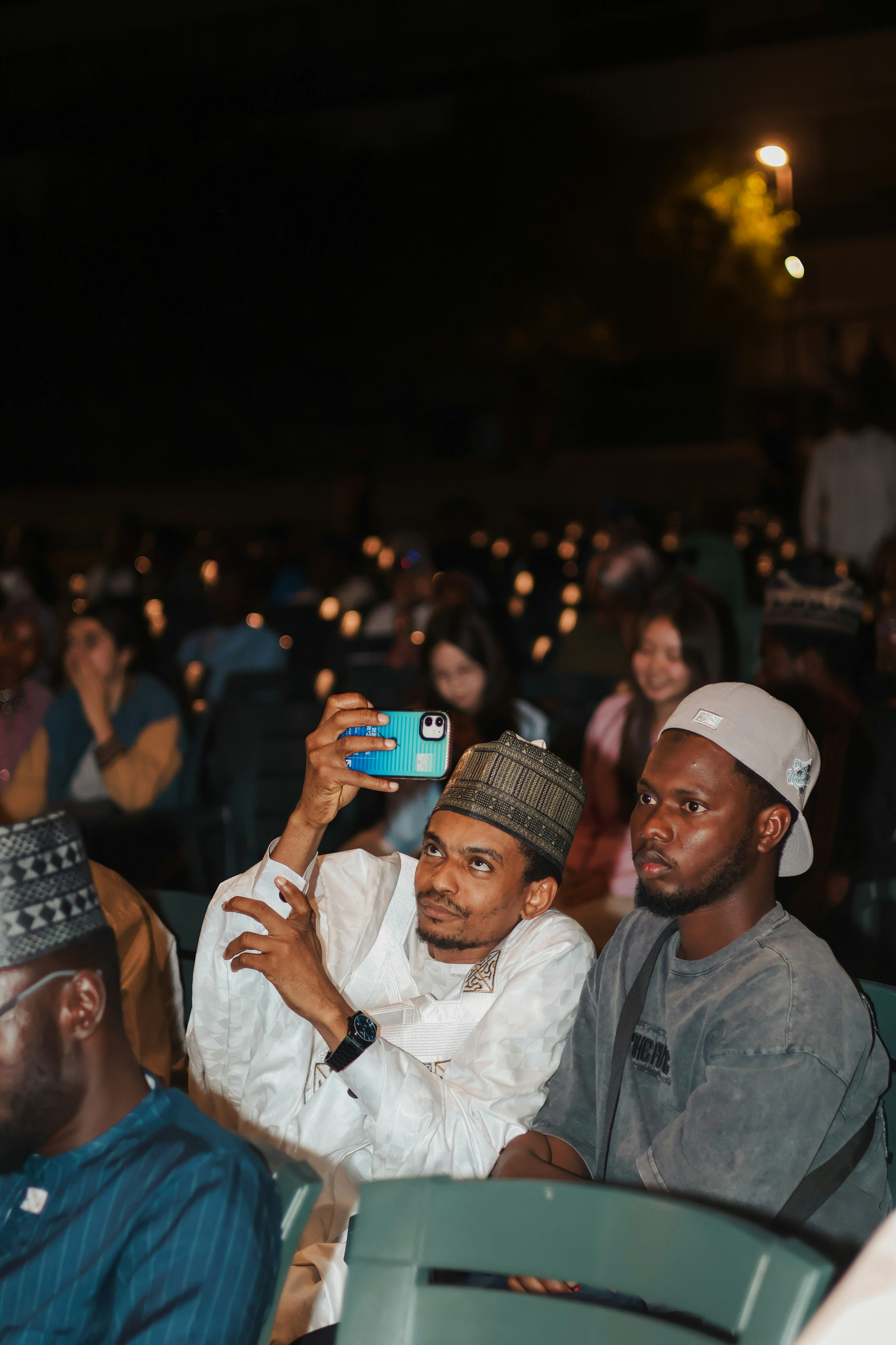 Man filming with phone in audience at outdoor event
