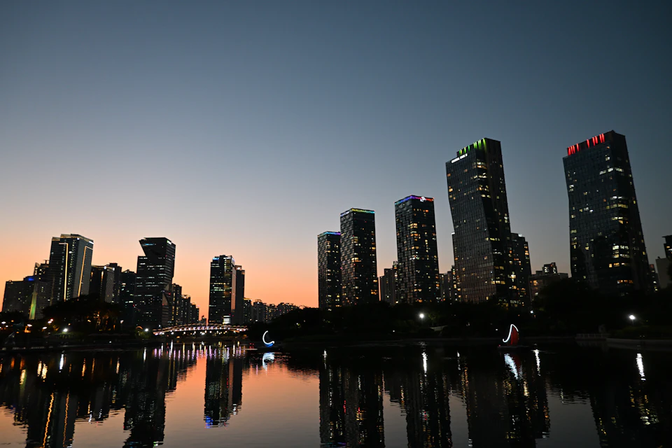 Tall buildings illuminated by colorful lights against a dark evening sky in cityscape