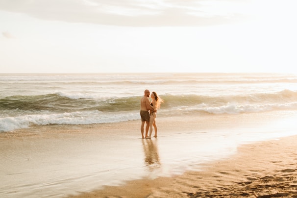 Couple embracing on a sandy beach at sunset.