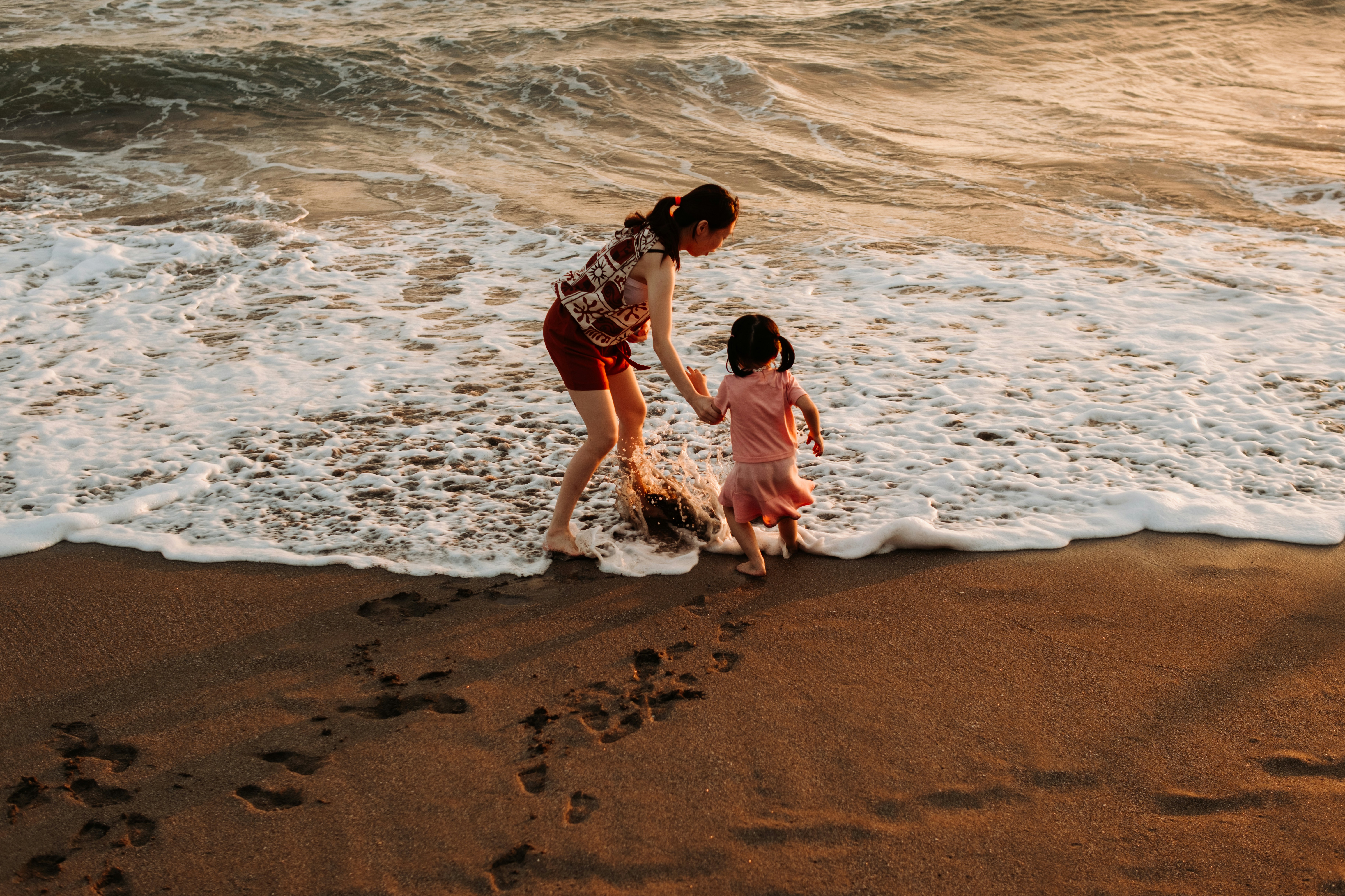Mother and child walking on a beach at sunset