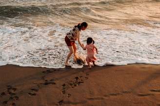 Mother and child walking on a beach at sunset