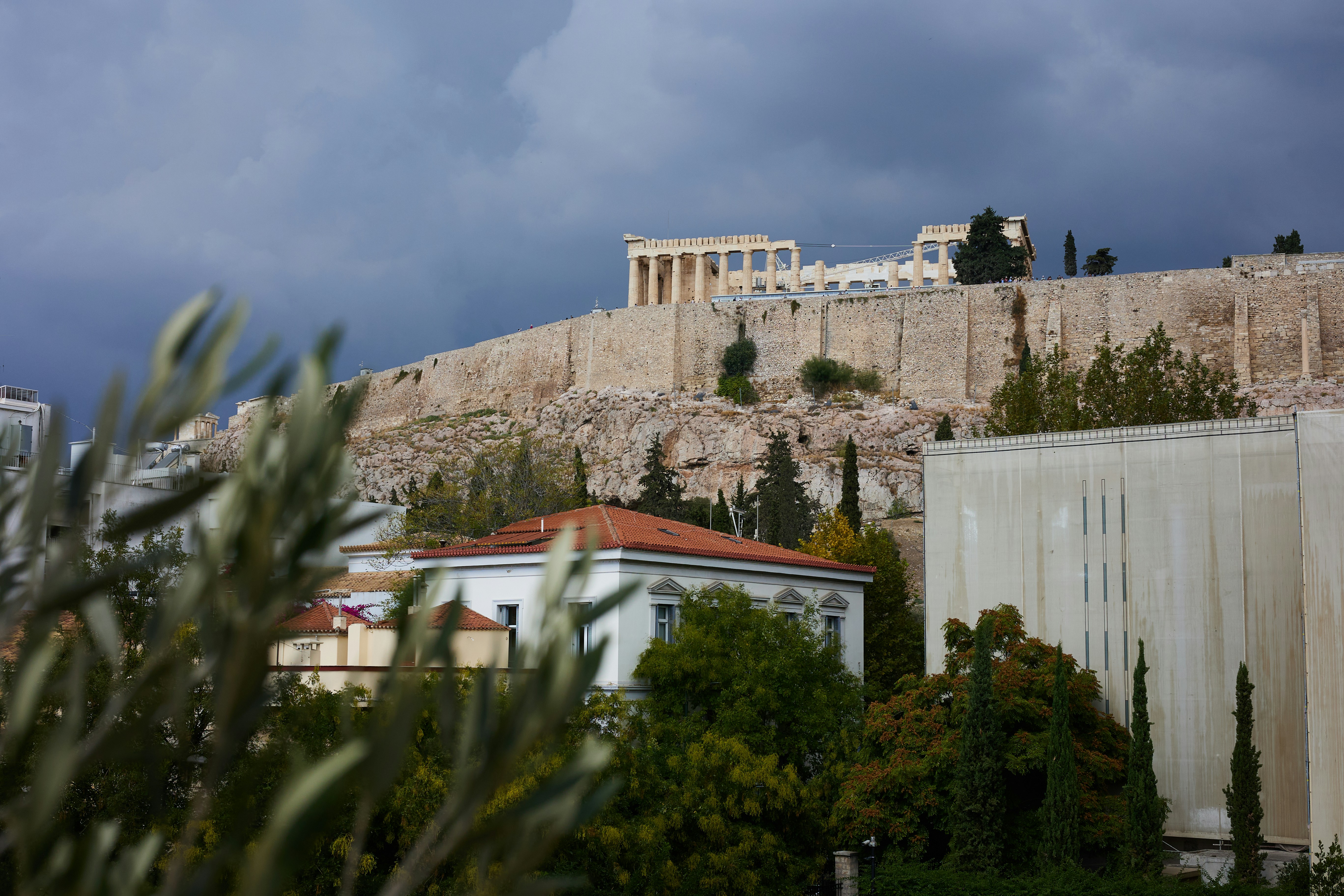 The acropolis of athens under a cloudy sky.