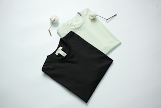Two t-shirts, black and light green, with cotton stems.