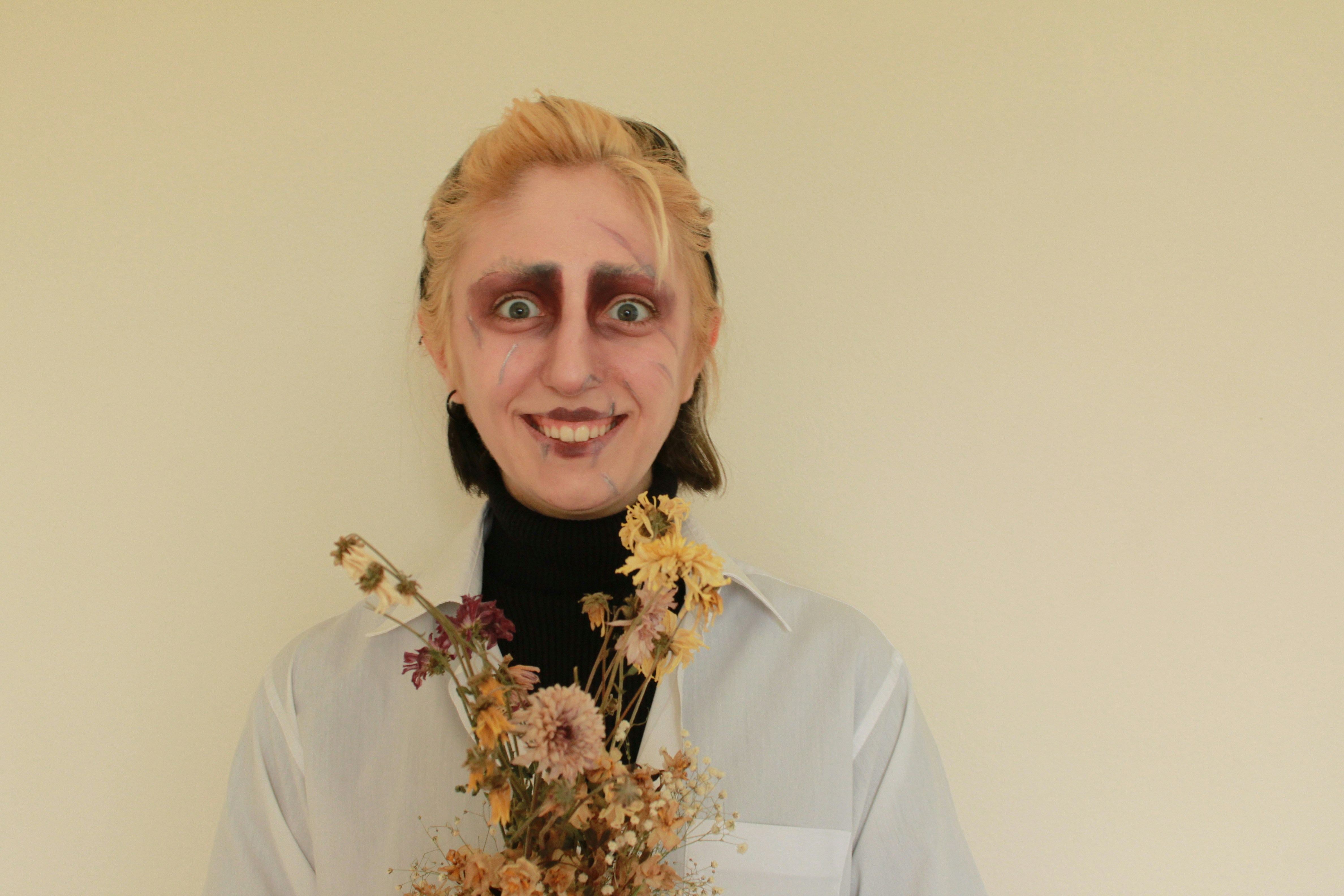 Person with dramatic makeup holding dried flowers