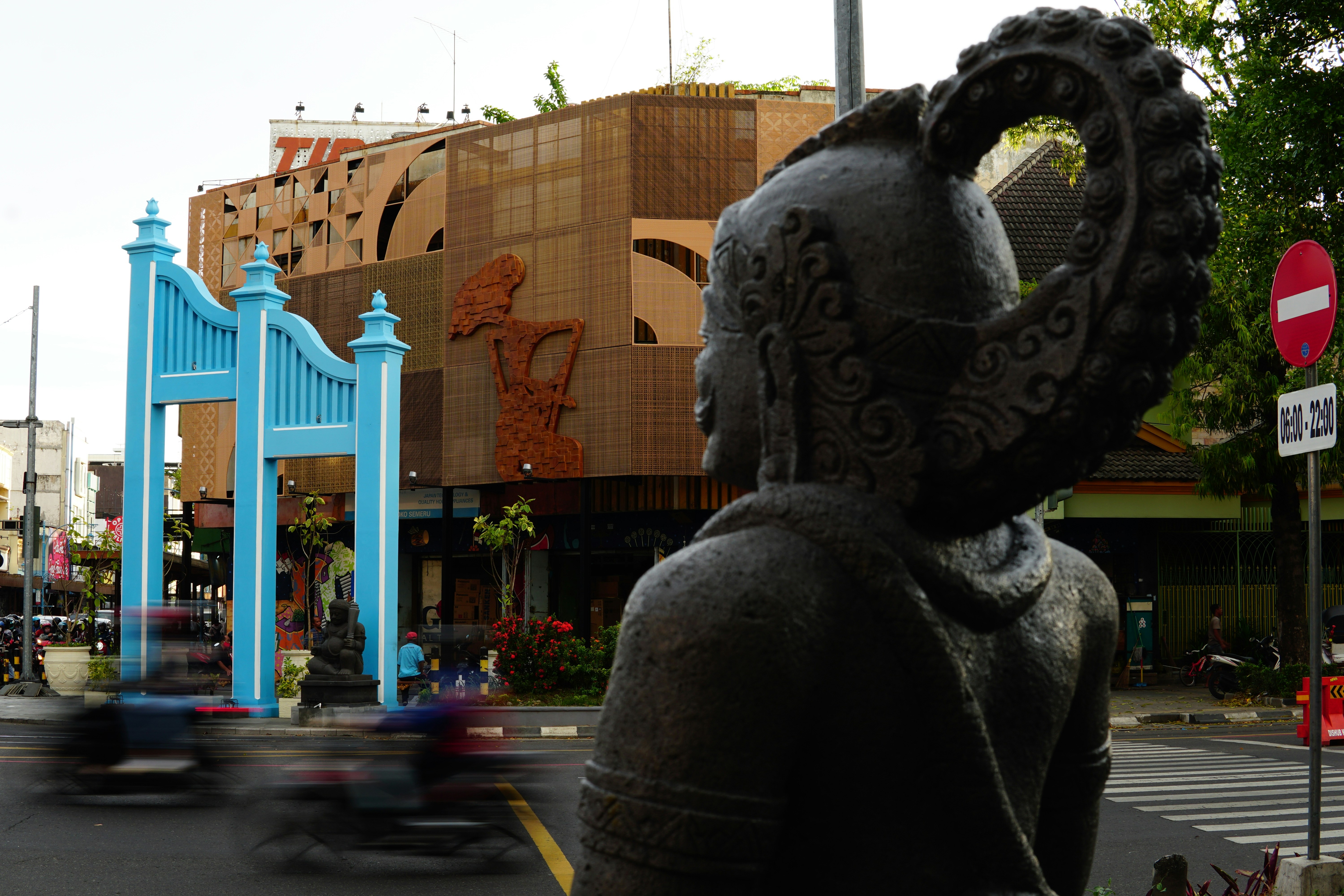 Statue im Vordergrund mit belebter Straße und Gebäude