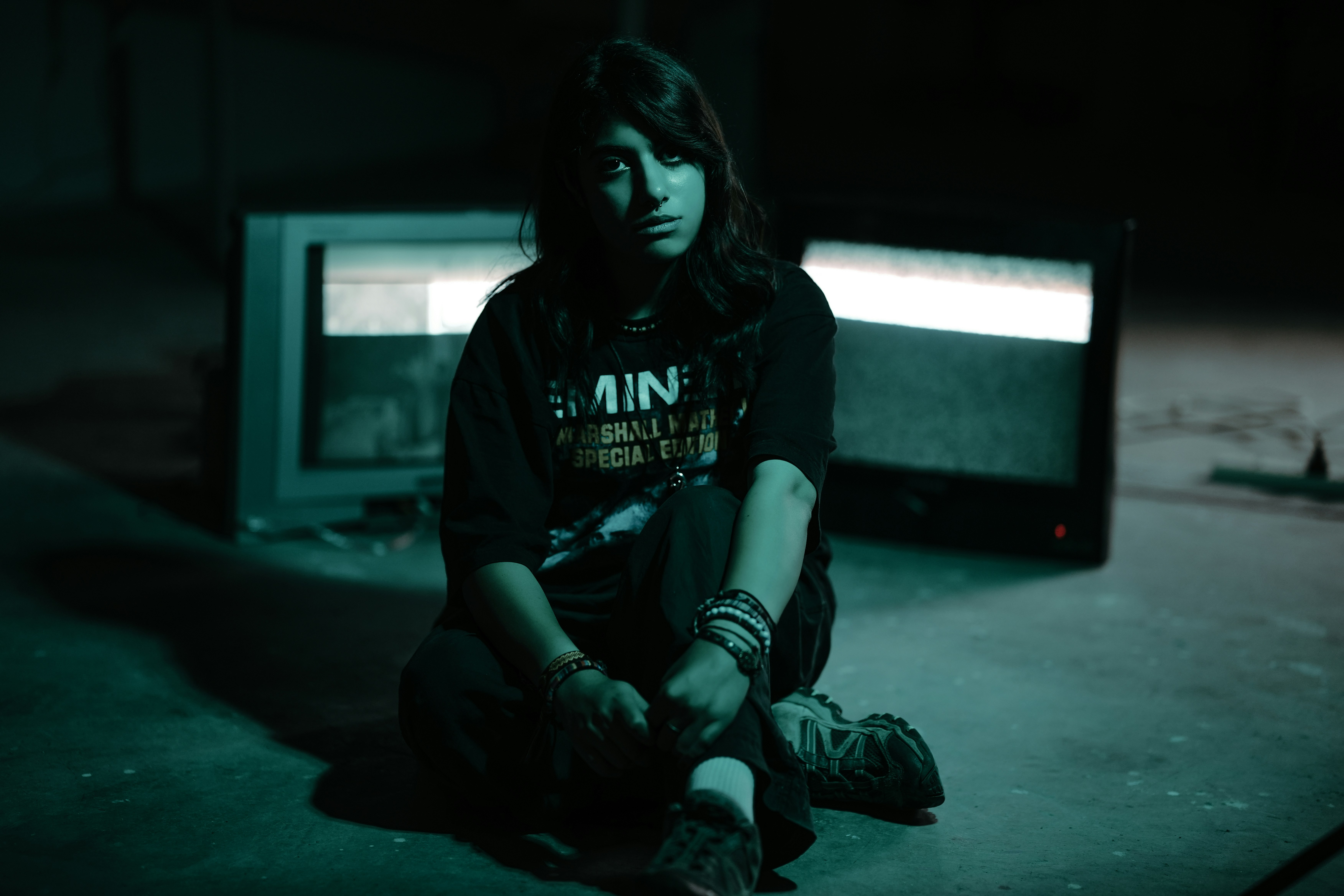Woman sitting on floor with two old televisions