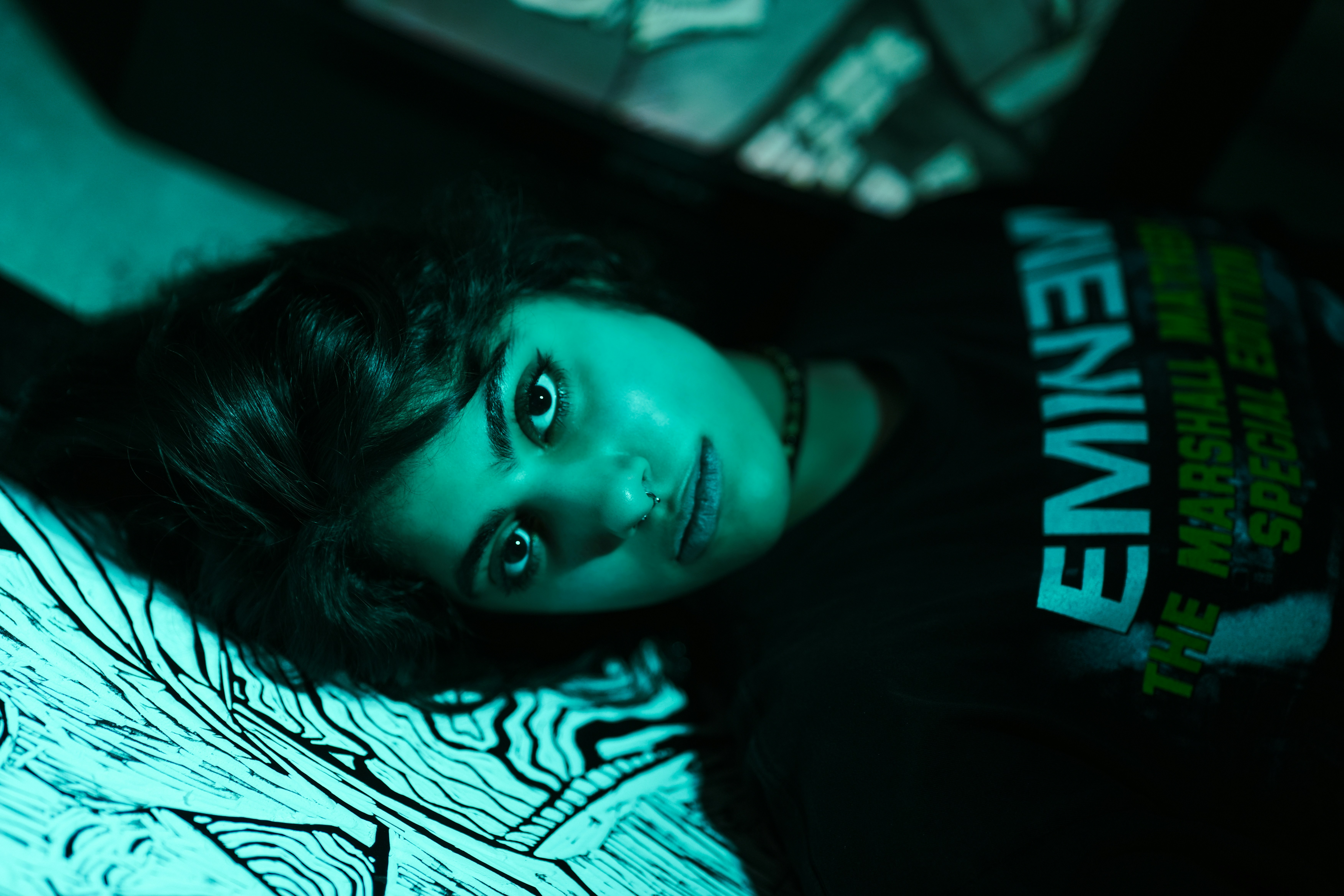 Young woman in eminem shirt lies on bed (Photo by lhon karwan on Unsplash)