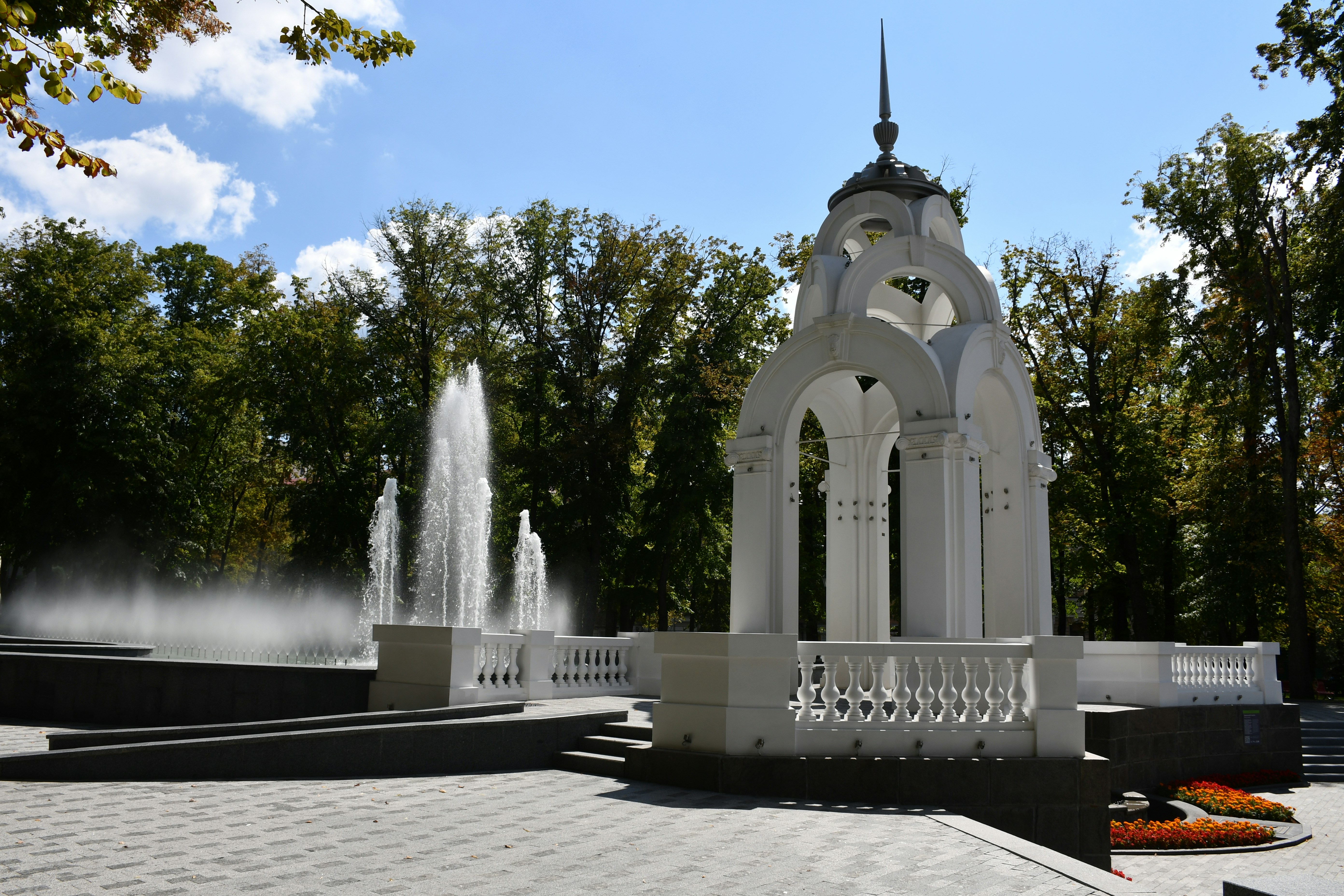 White ornate structure beside a large public fountain.
