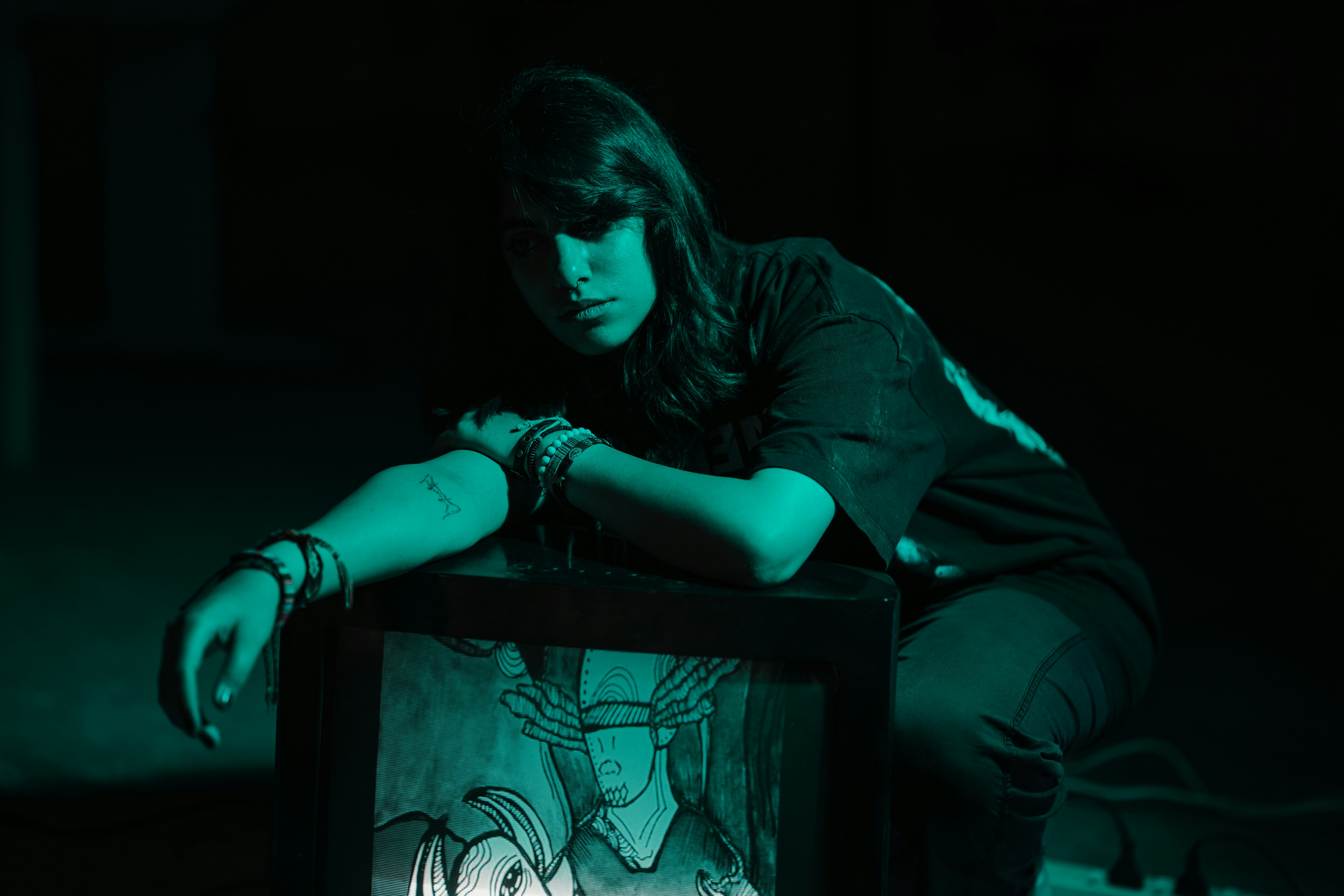 Young woman in dark room with teal lighting.