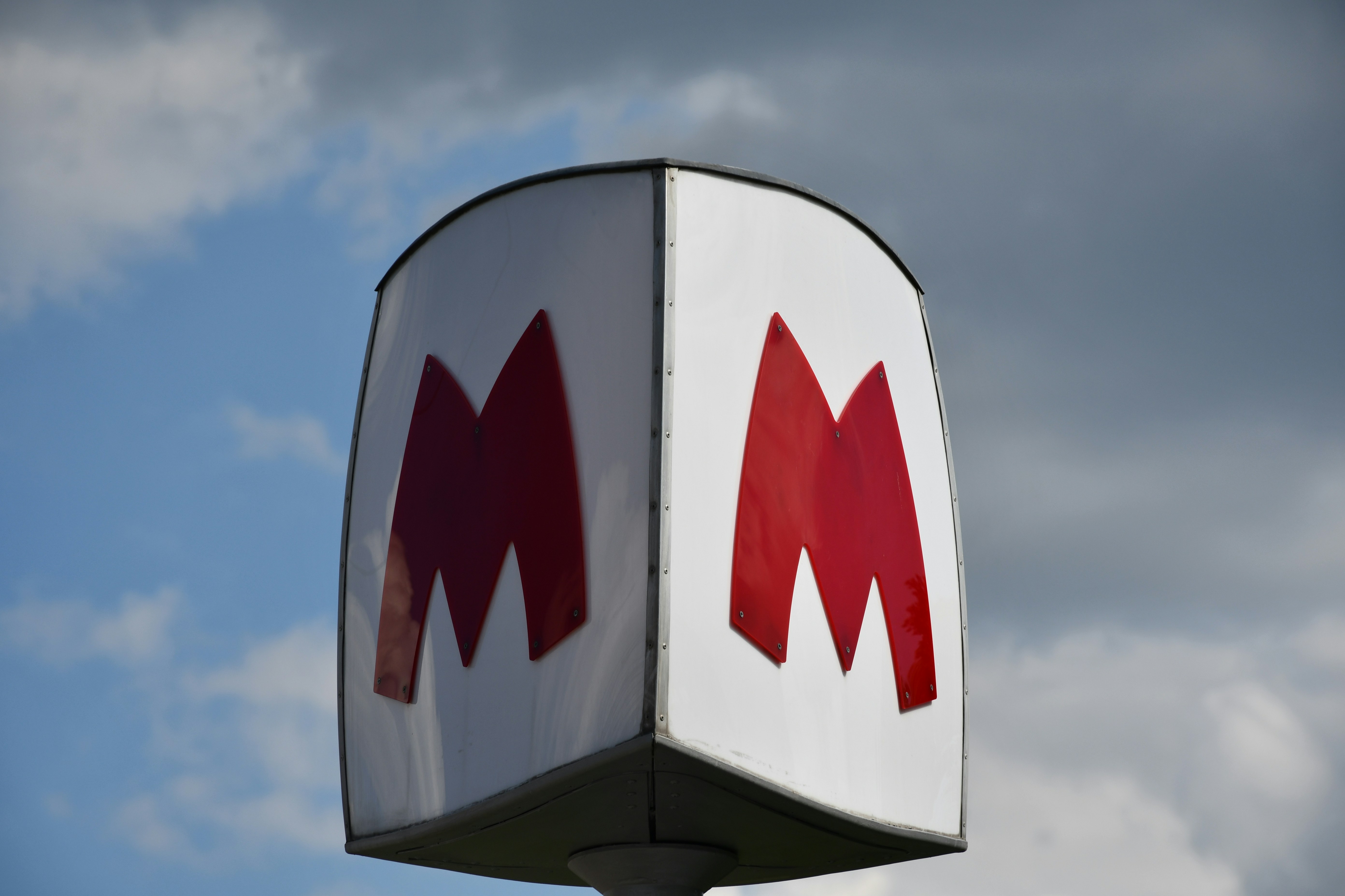Metro sign with red m logo against sky