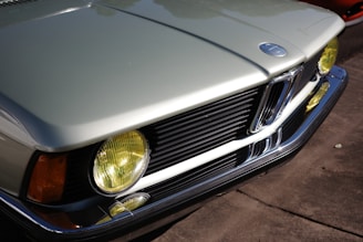 Silver vintage car with yellow headlights and chrome grille.