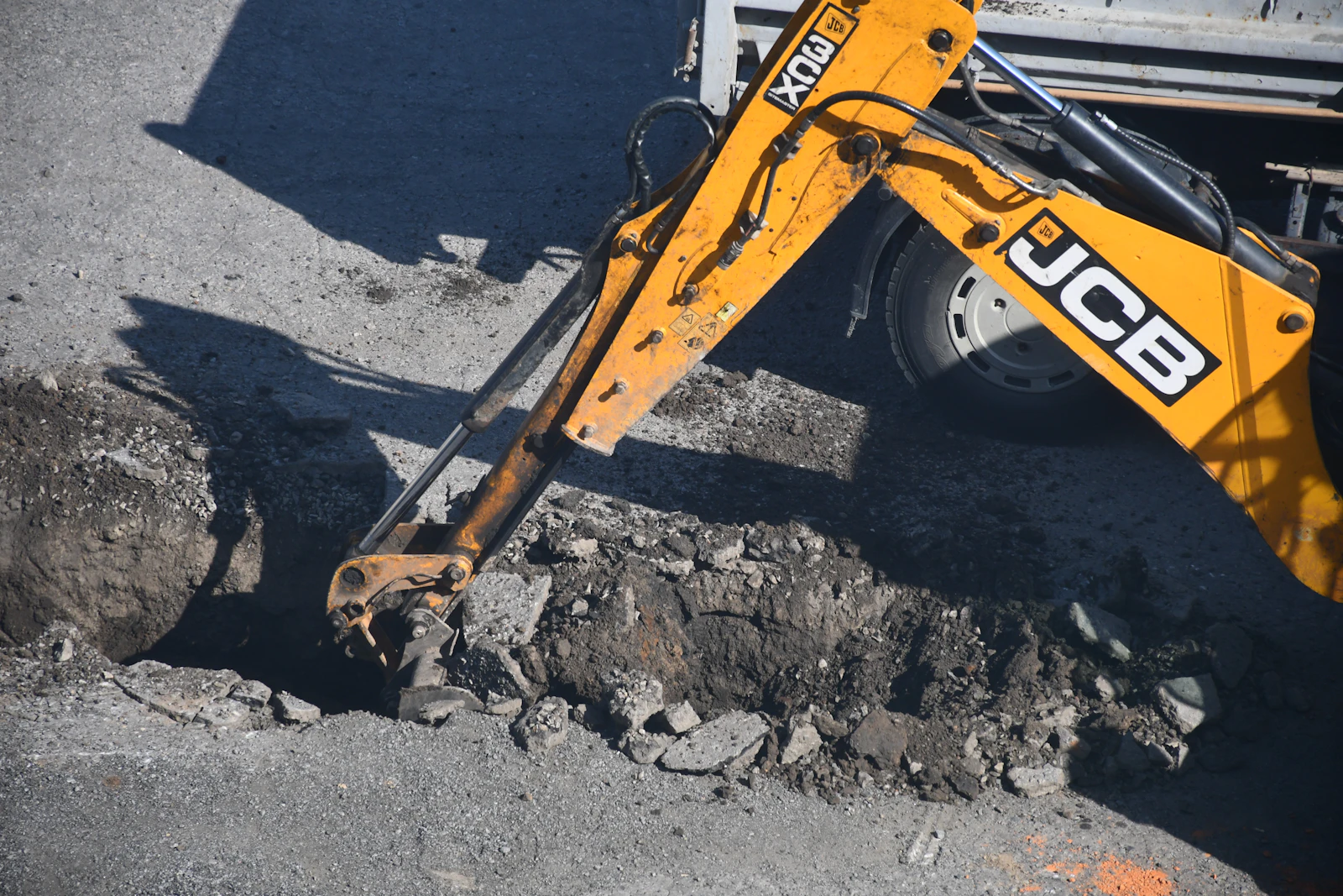 Yellow excavator digging a utility trench