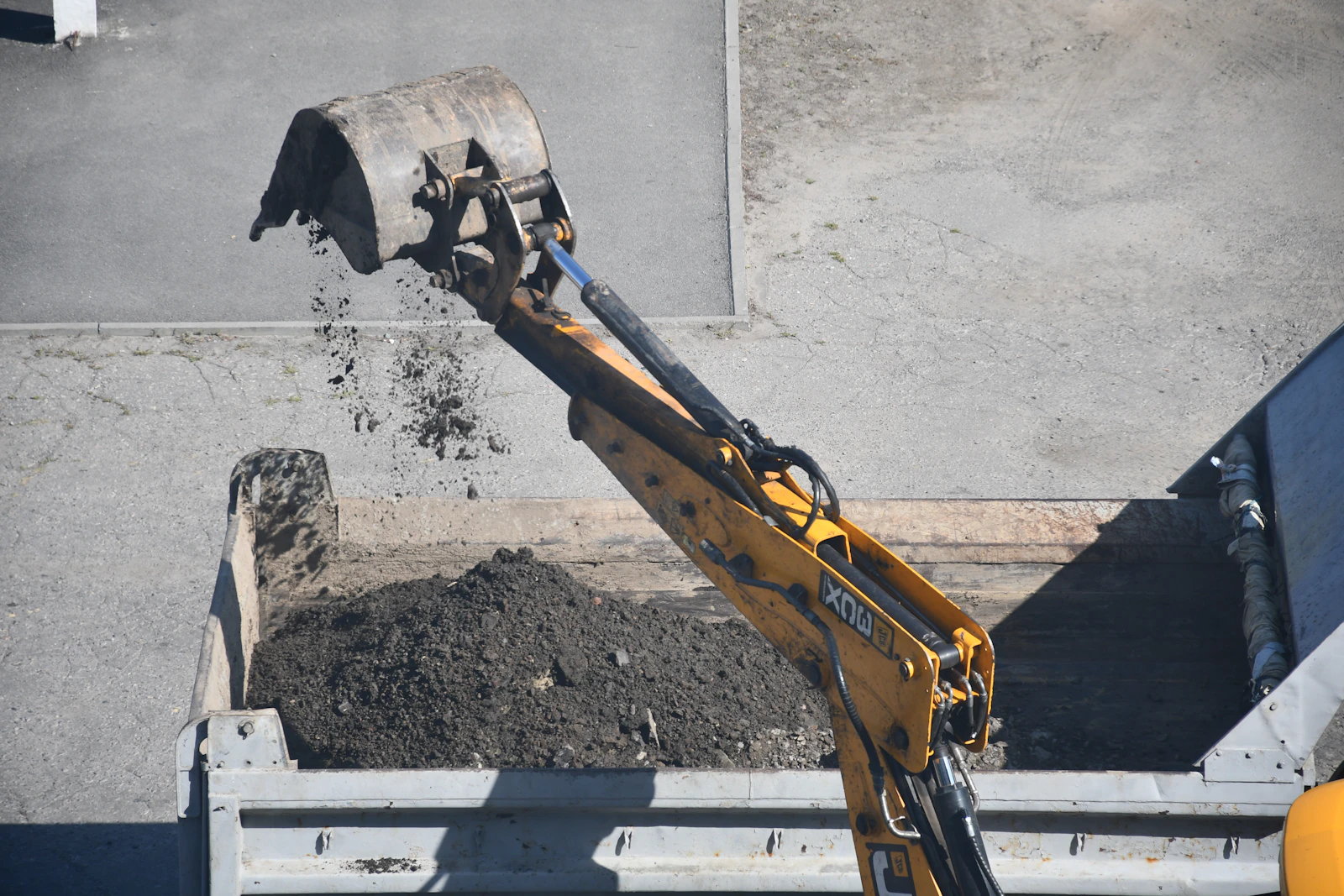 An excavator loading cleared material into a truck