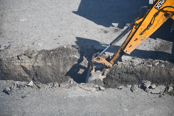 Excavator Digging Trench in Road
