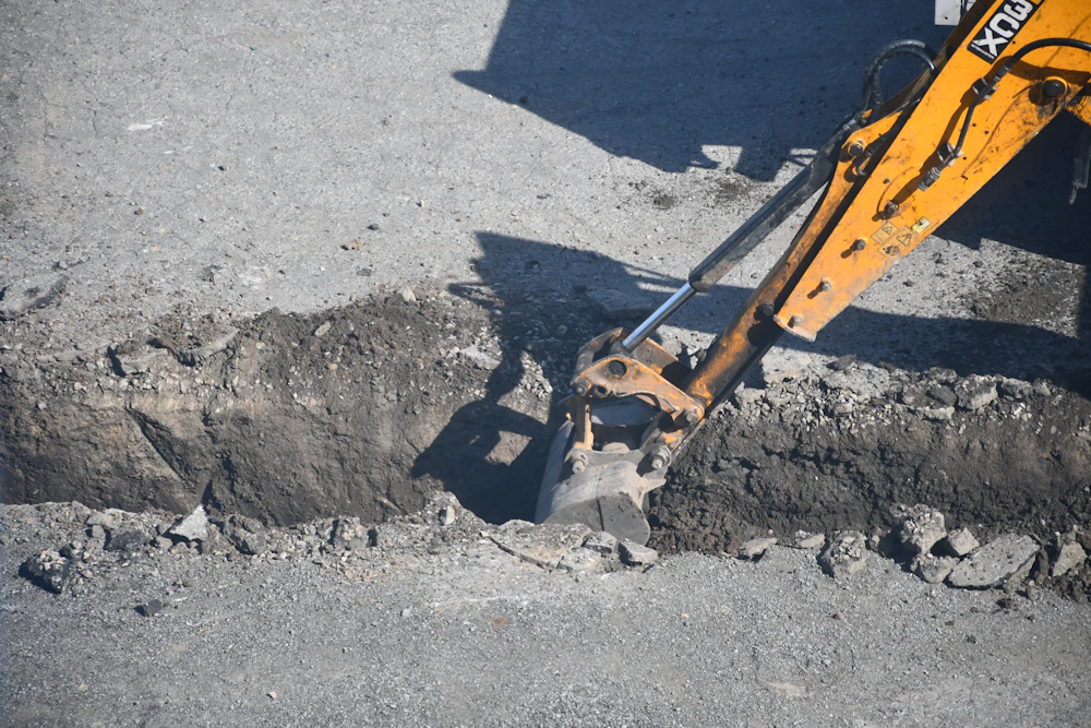 An excavator opening a trench in a roadway for sewer line work